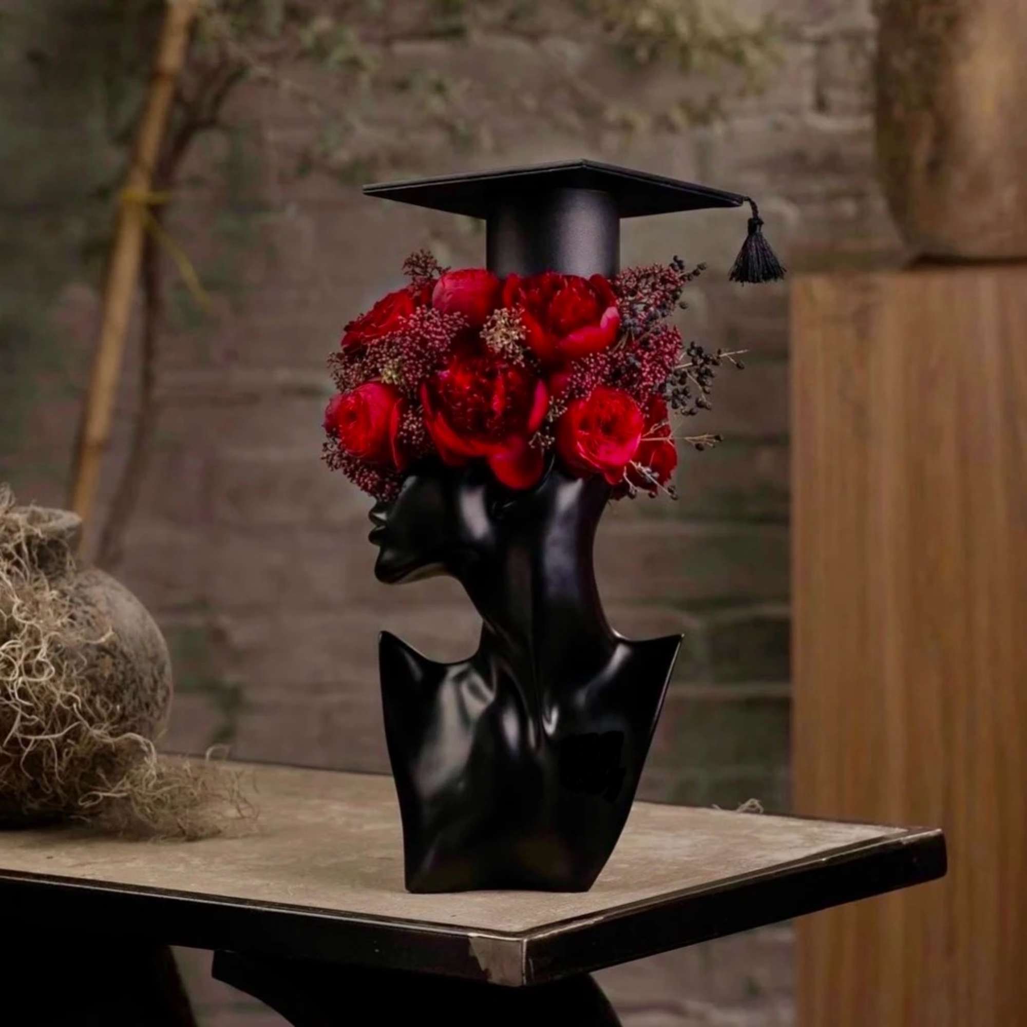 Red roses arranged in a black graduation cap vase