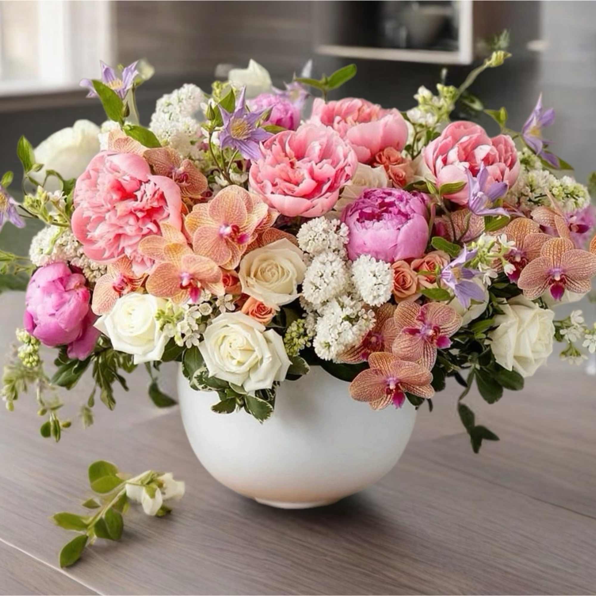 Pink and white floral arrangement in a white bowl vase