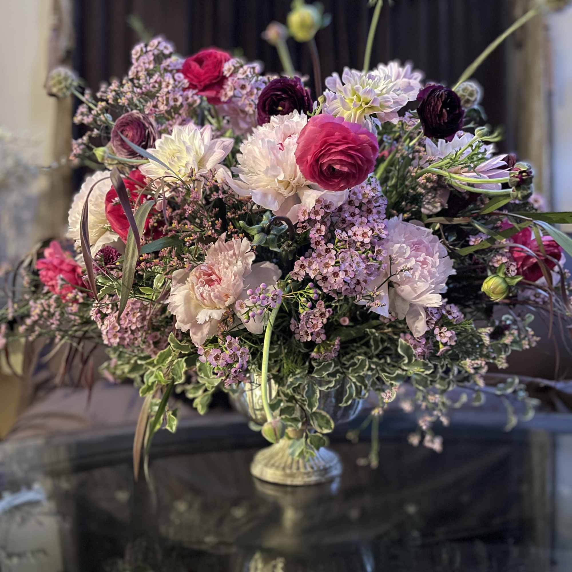 Large mixed floral arrangement in a pedestal vase with pink, white, and purple blooms