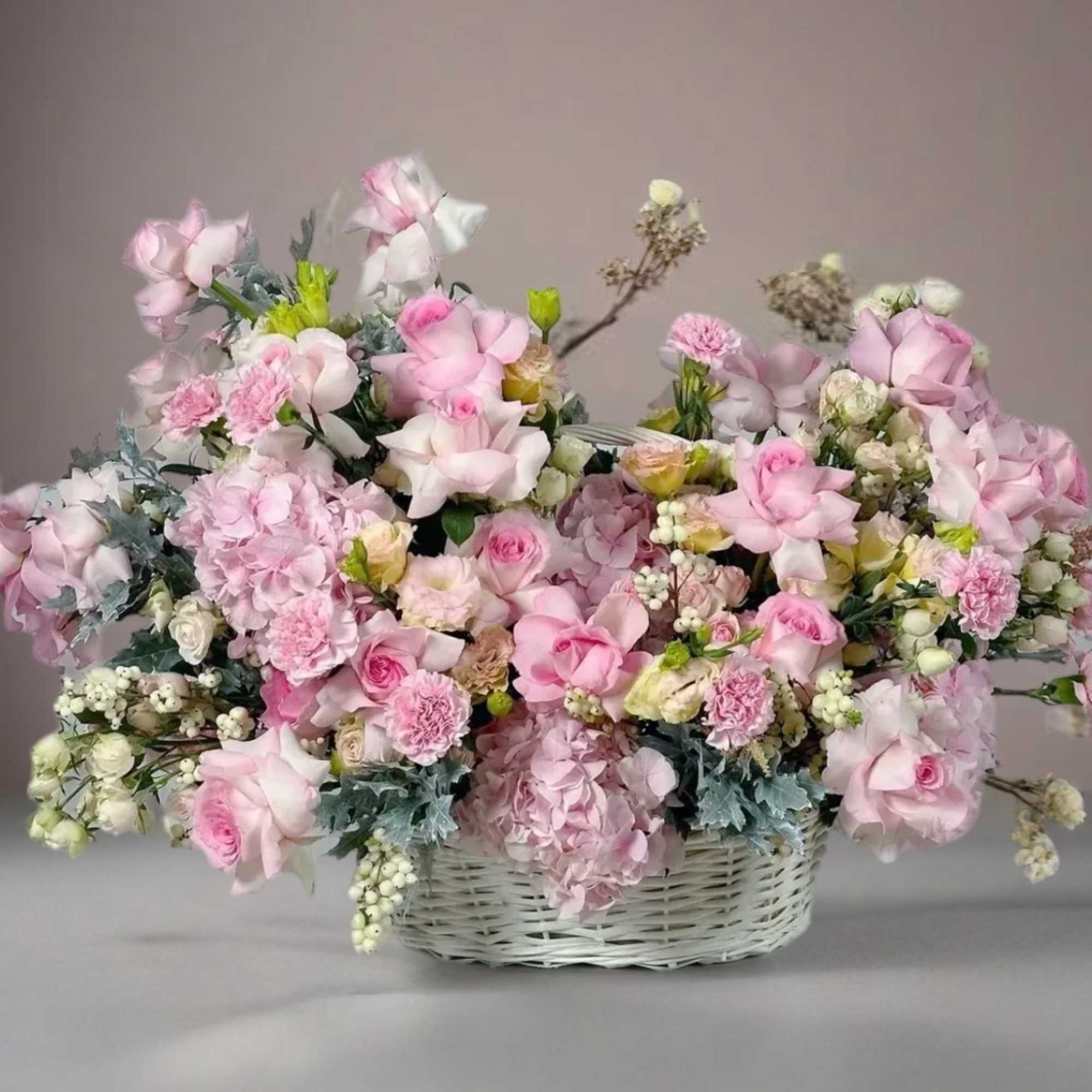 Large pink floral arrangement in a white wicker basket