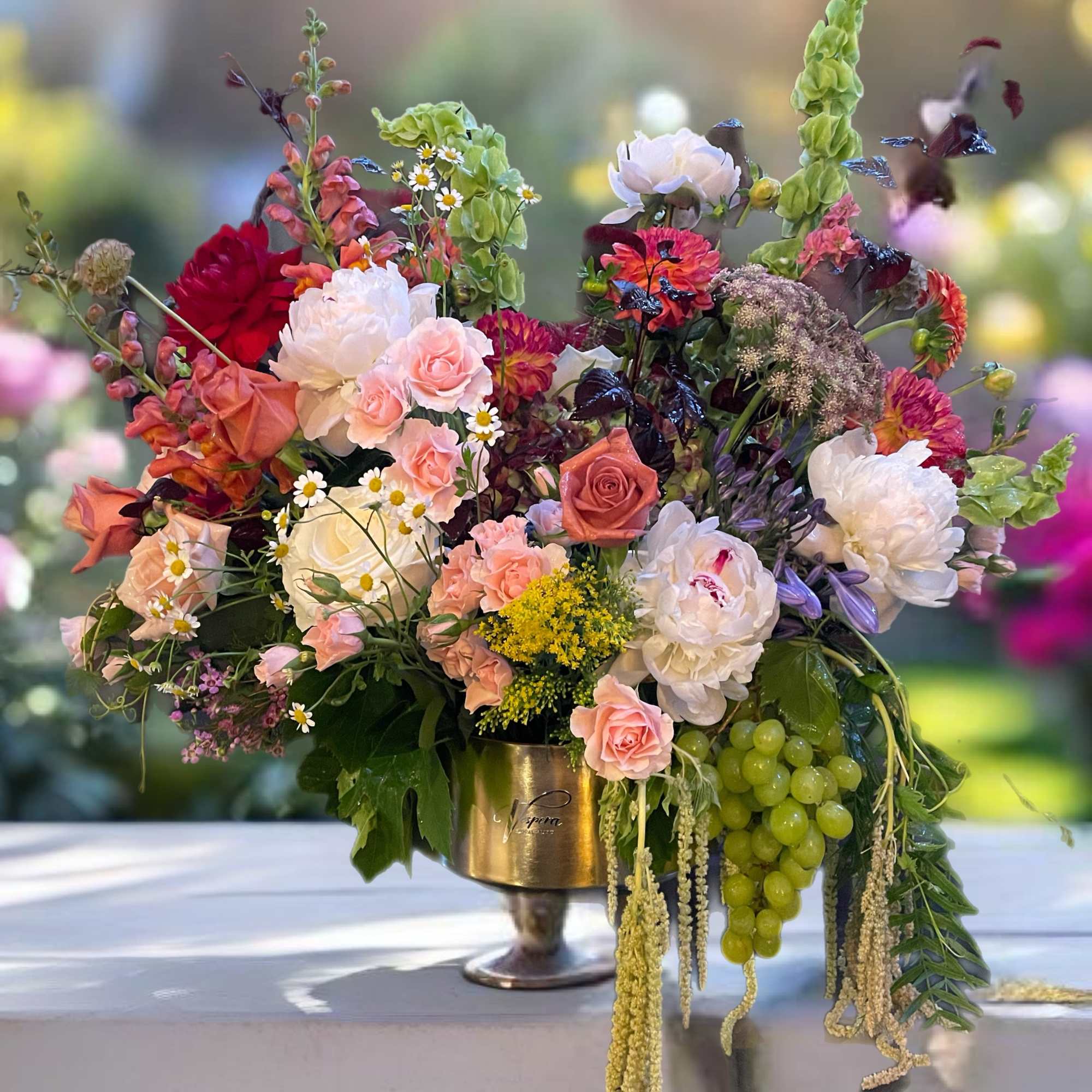 Large mixed floral arrangement in a gold pedestal vase