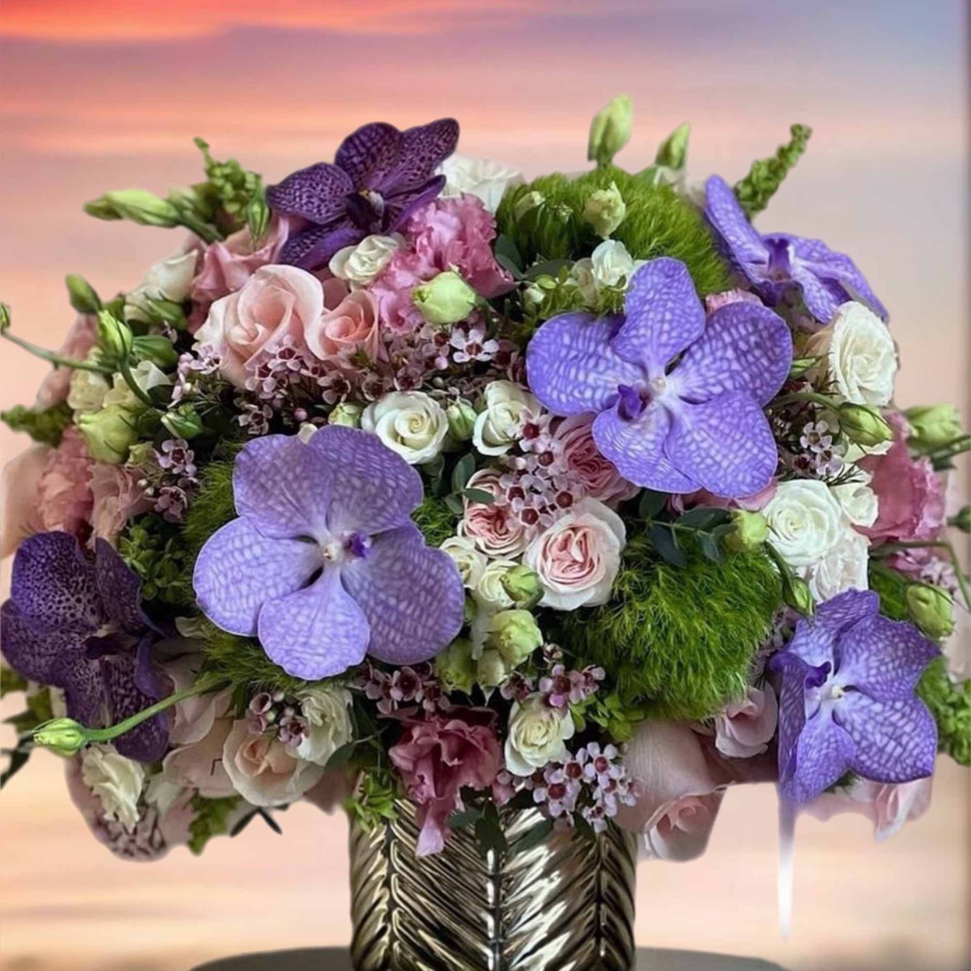 Bouquet of purple orchids and pink roses in a metallic vase