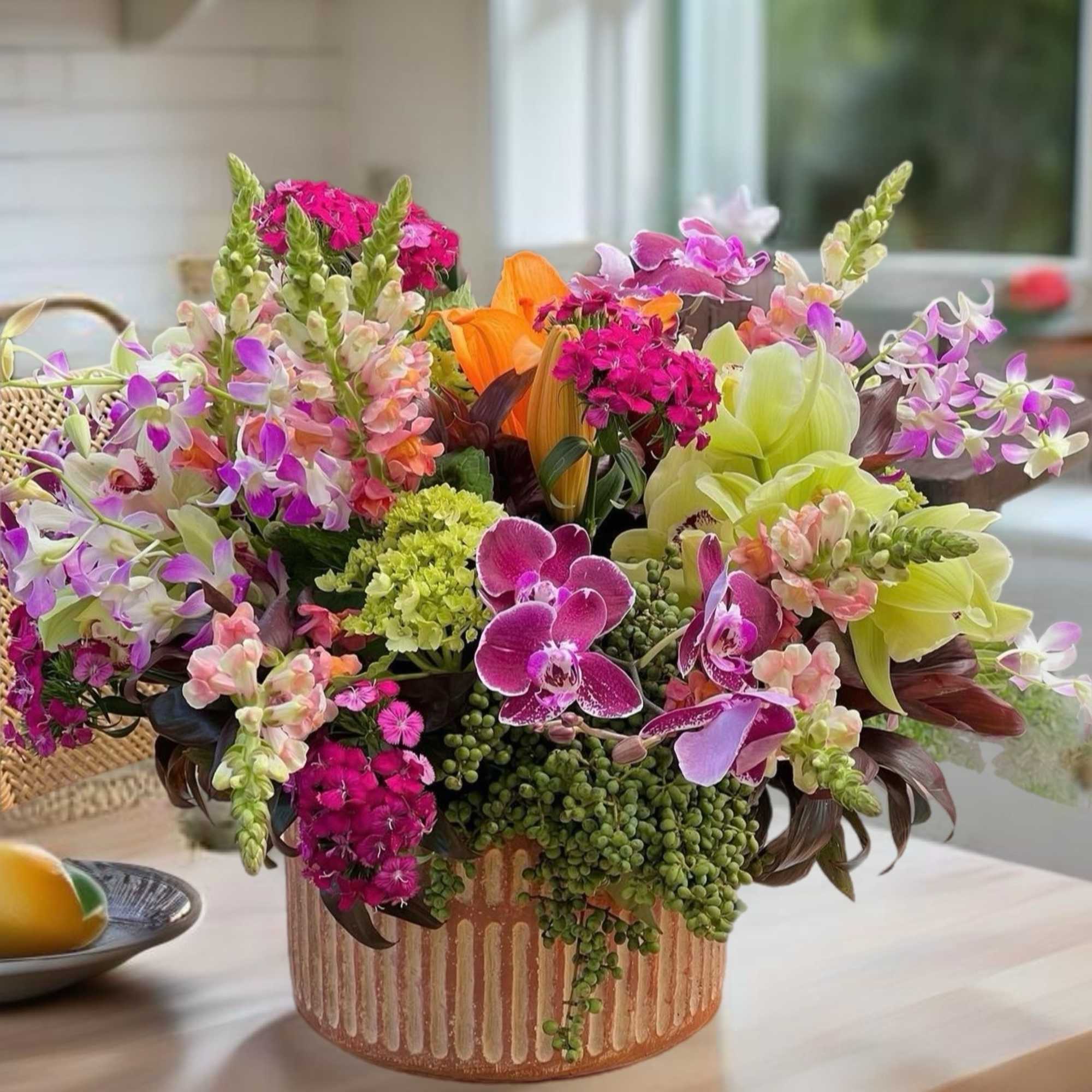 Mixed orchid and snapdragon arrangement in a striped ceramic vase