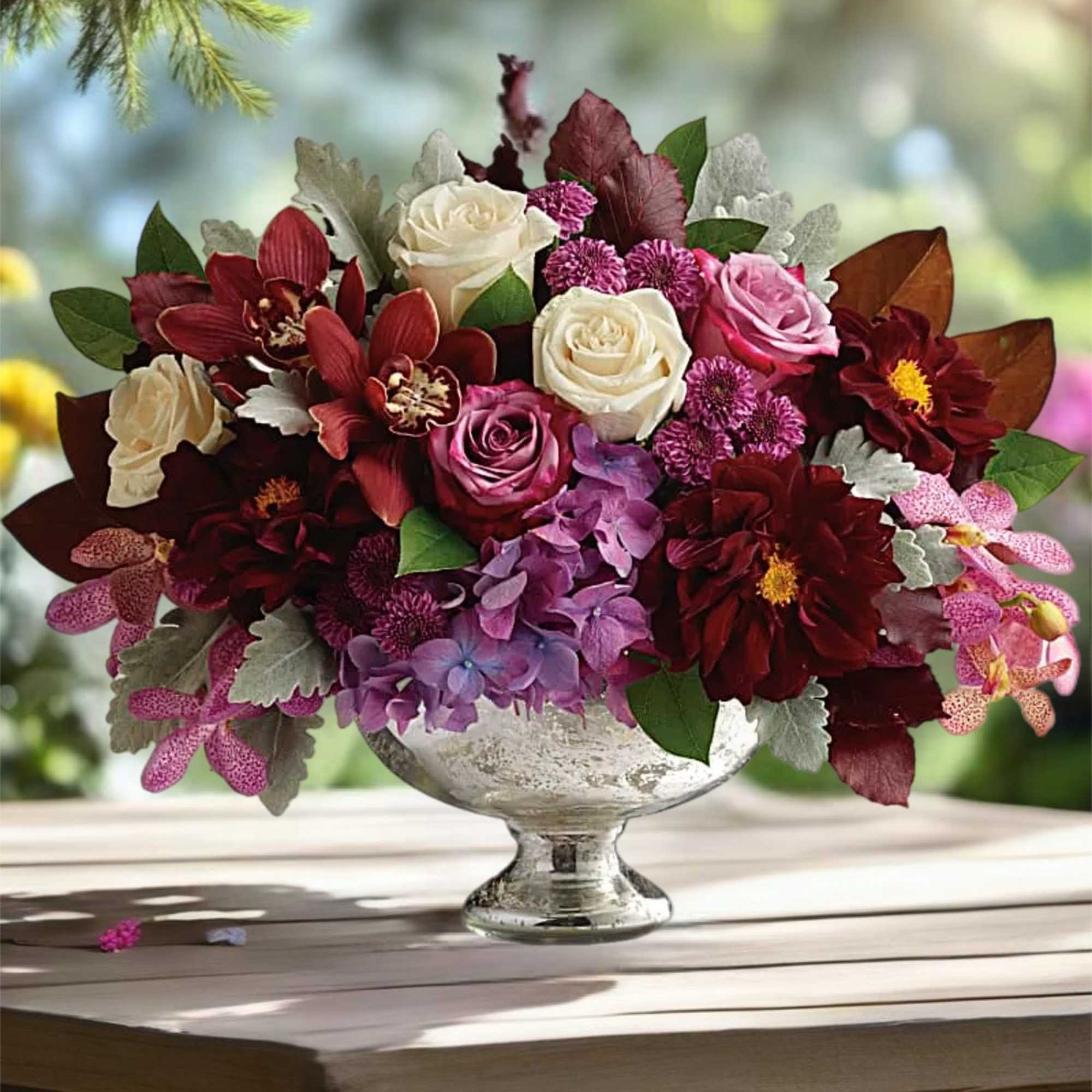 Mixed bouquet of roses and orchids in a silver pedestal vase