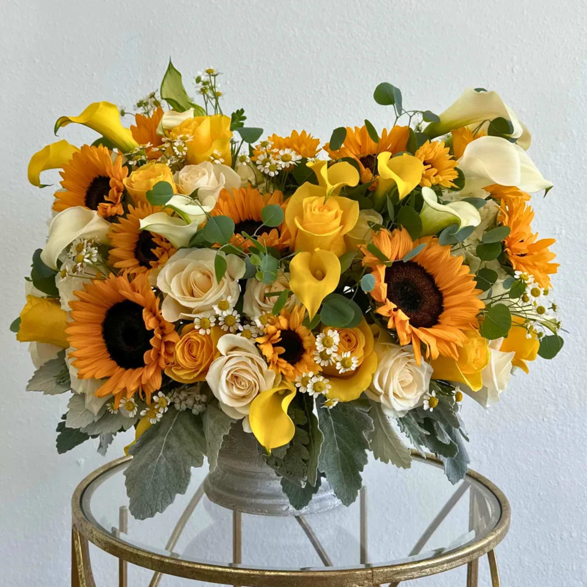 Bouquet of sunflowers, roses, and yellow calla lilies in a vase