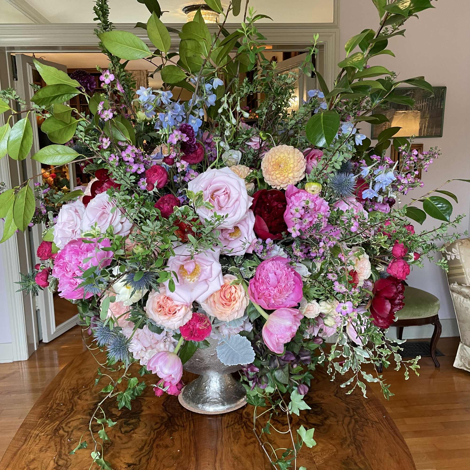 Large mixed floral arrangement in a silver vase with pink, white, and blue blooms