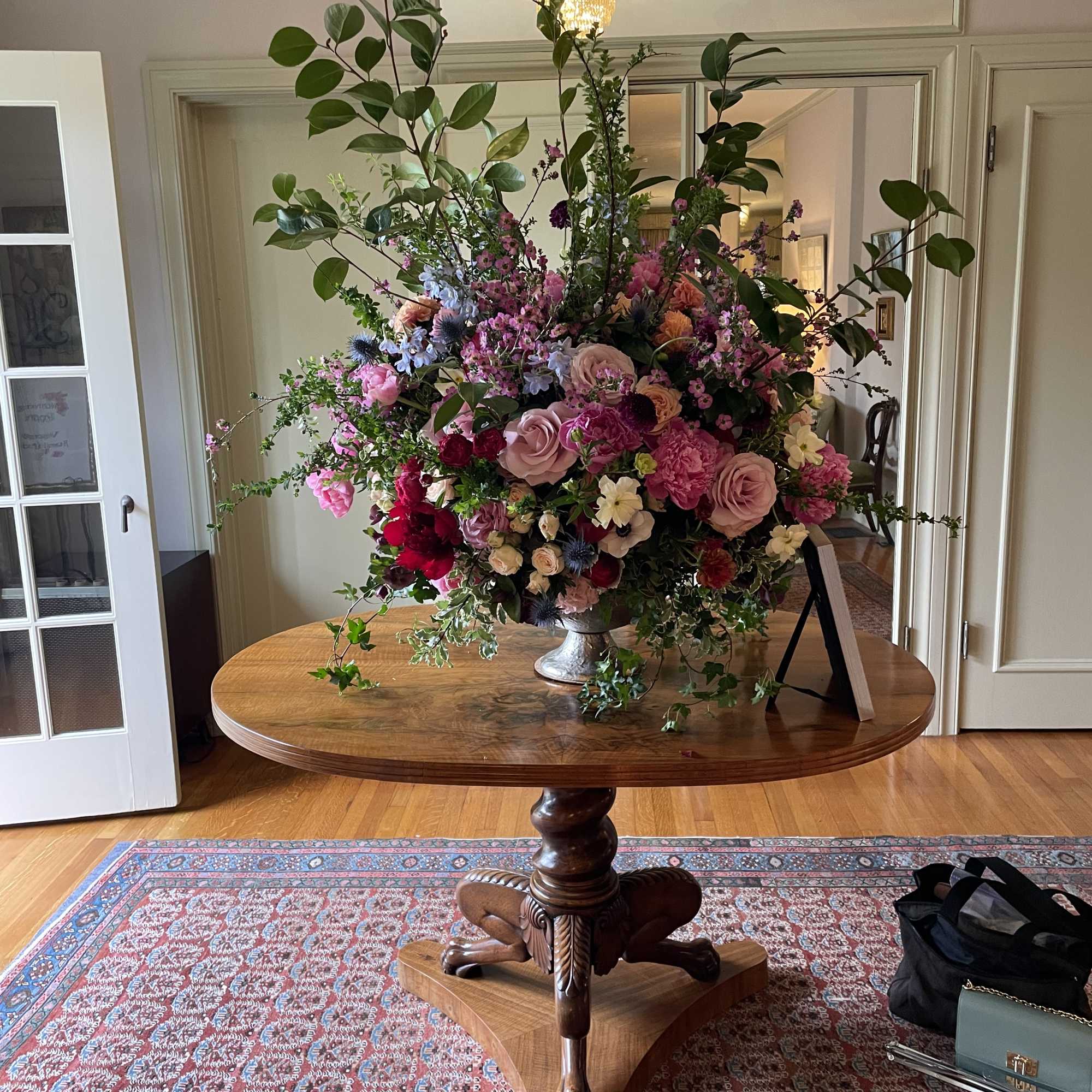 Large mixed floral arrangement in a silver vase on a wooden table