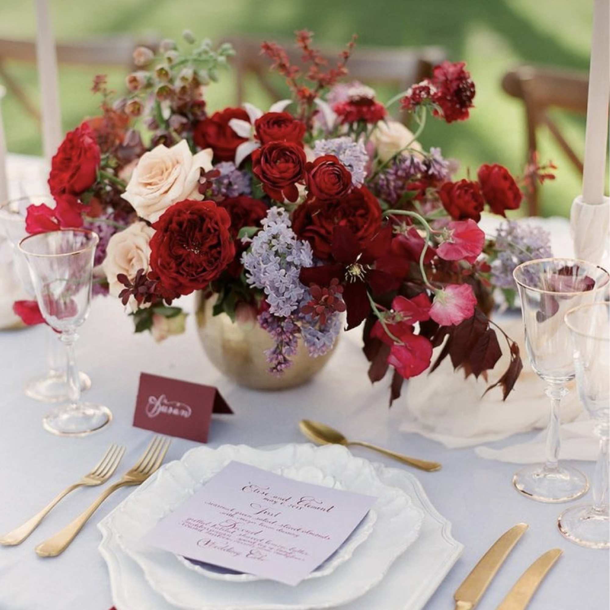 Red and blush floral centerpiece in a gold vase on a set table