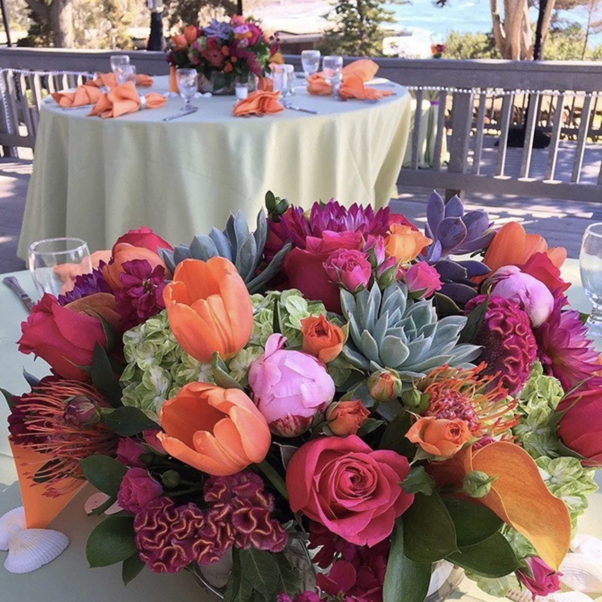 Bright mixed floral centerpiece with tulips, roses, and succulents on a table