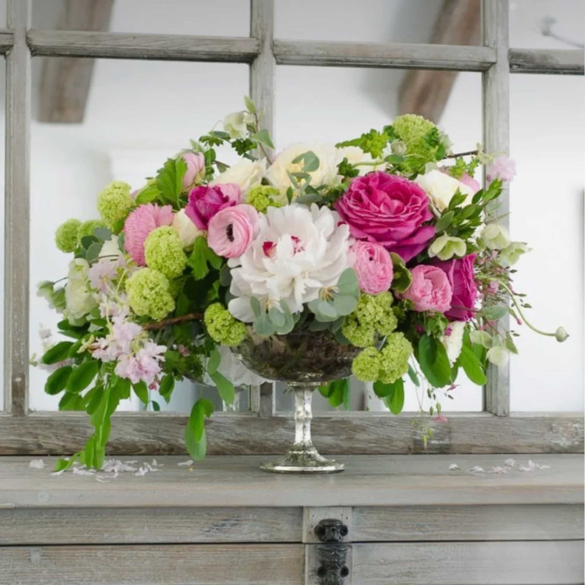 Pink and white floral arrangement in a silver pedestal bowl