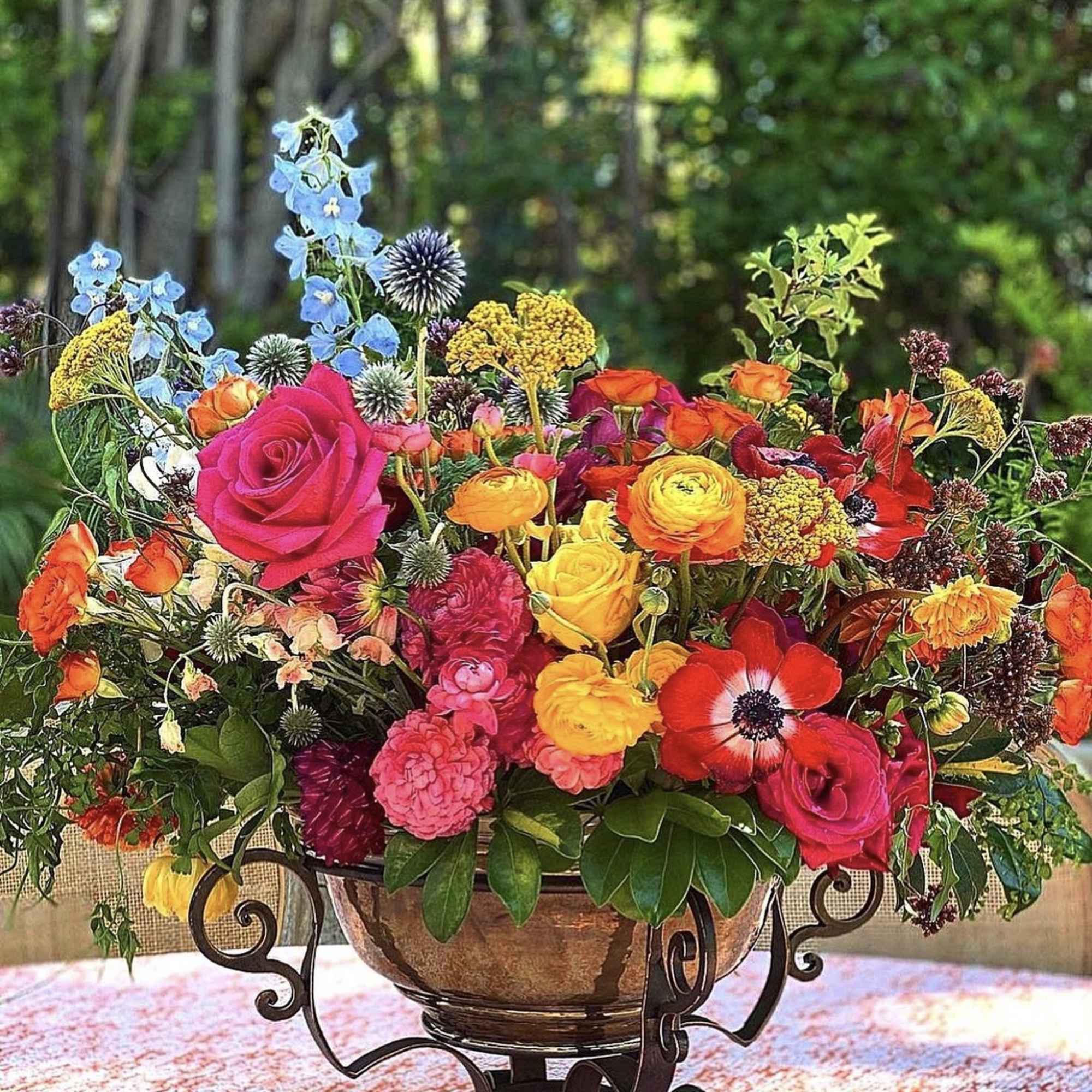 Colorful mixed flower arrangement in a decorative bowl on a metal stand
