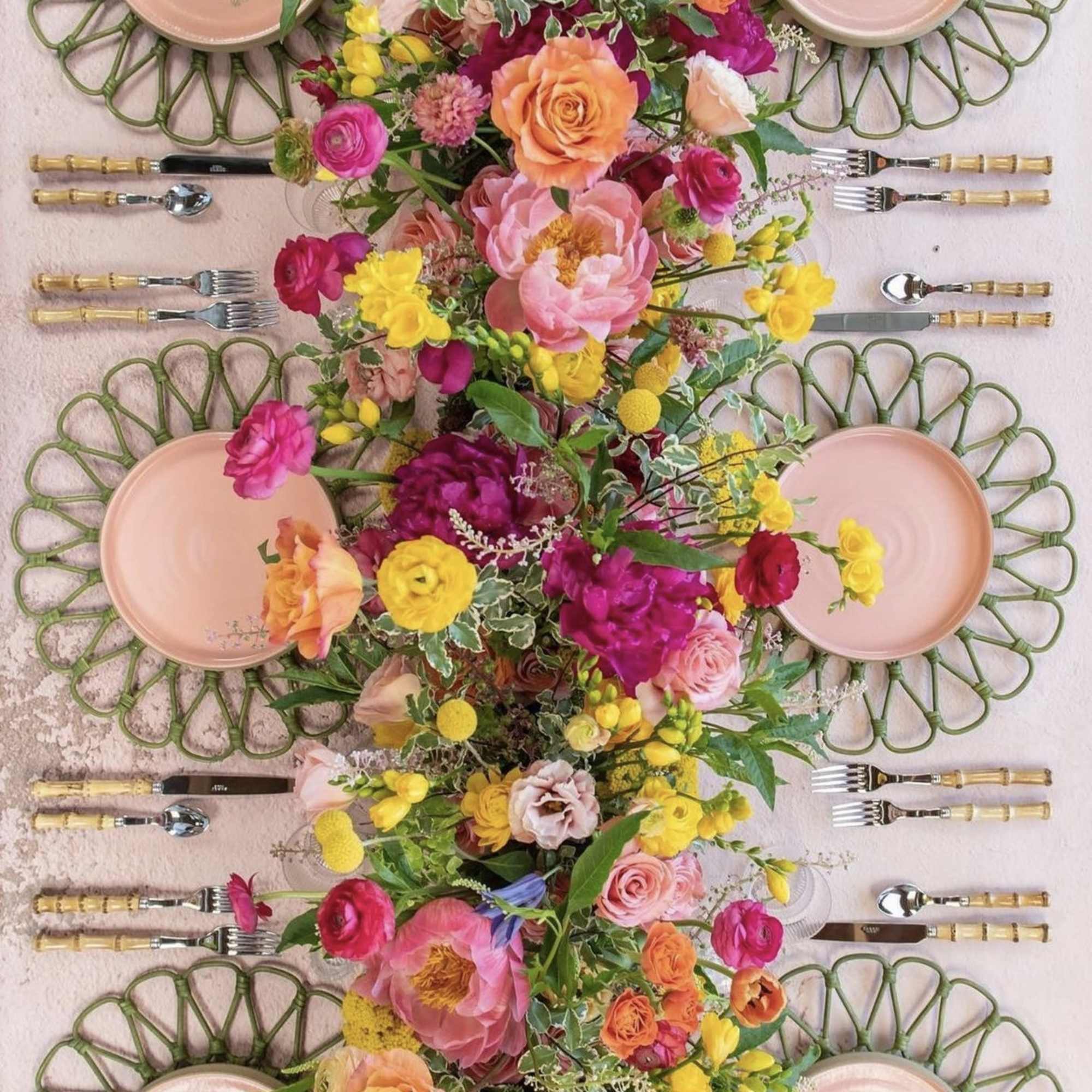 Long floral table runner with pink, yellow, and orange blooms on a set dining table