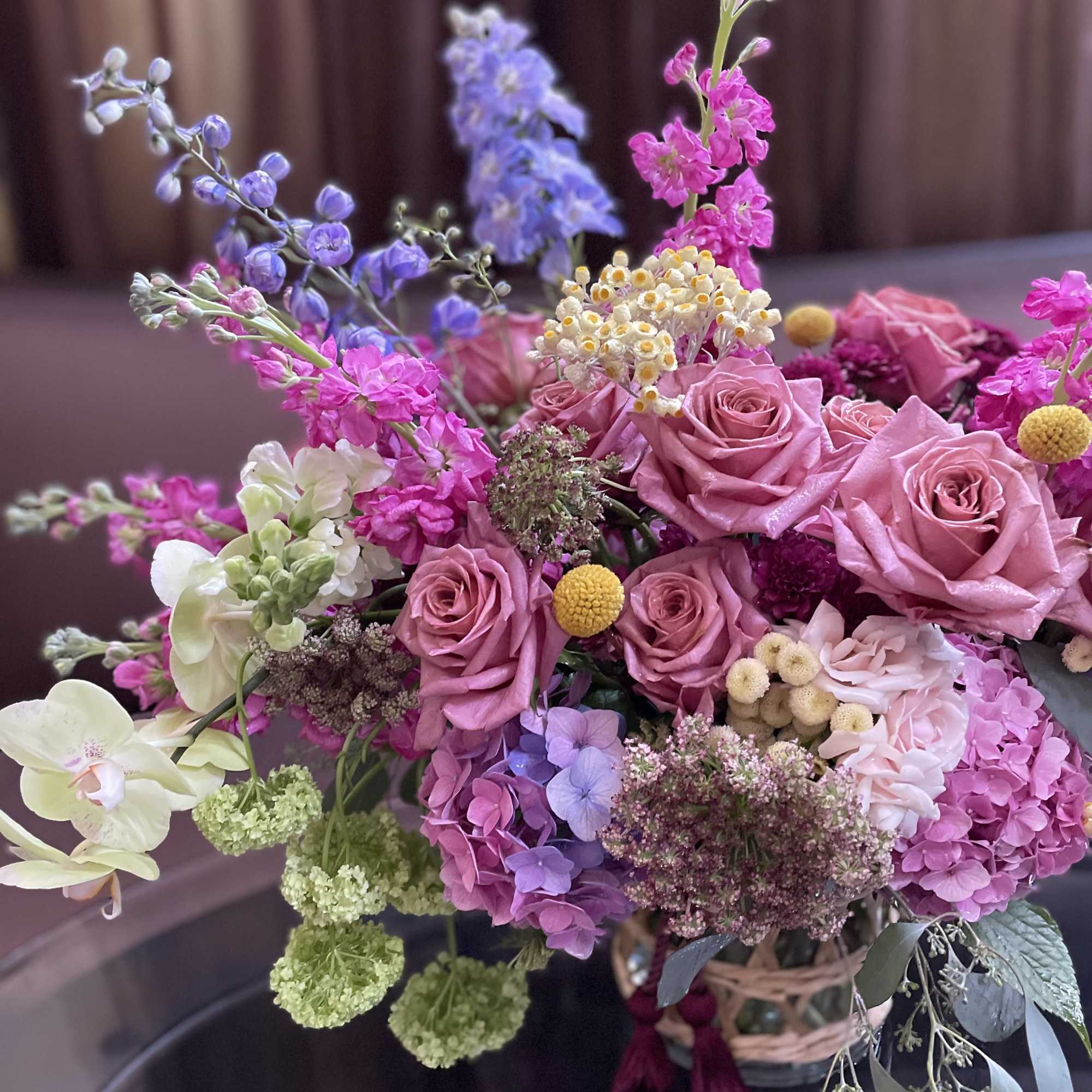 Pink and lavender bouquet with roses and mixed blooms in a basket