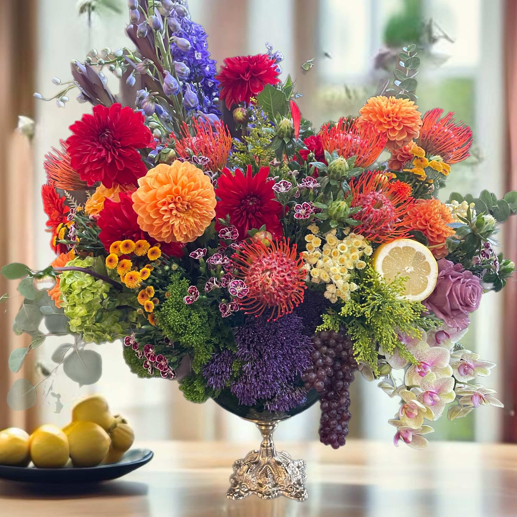 Colorful mixed flower arrangement in a silver pedestal vase