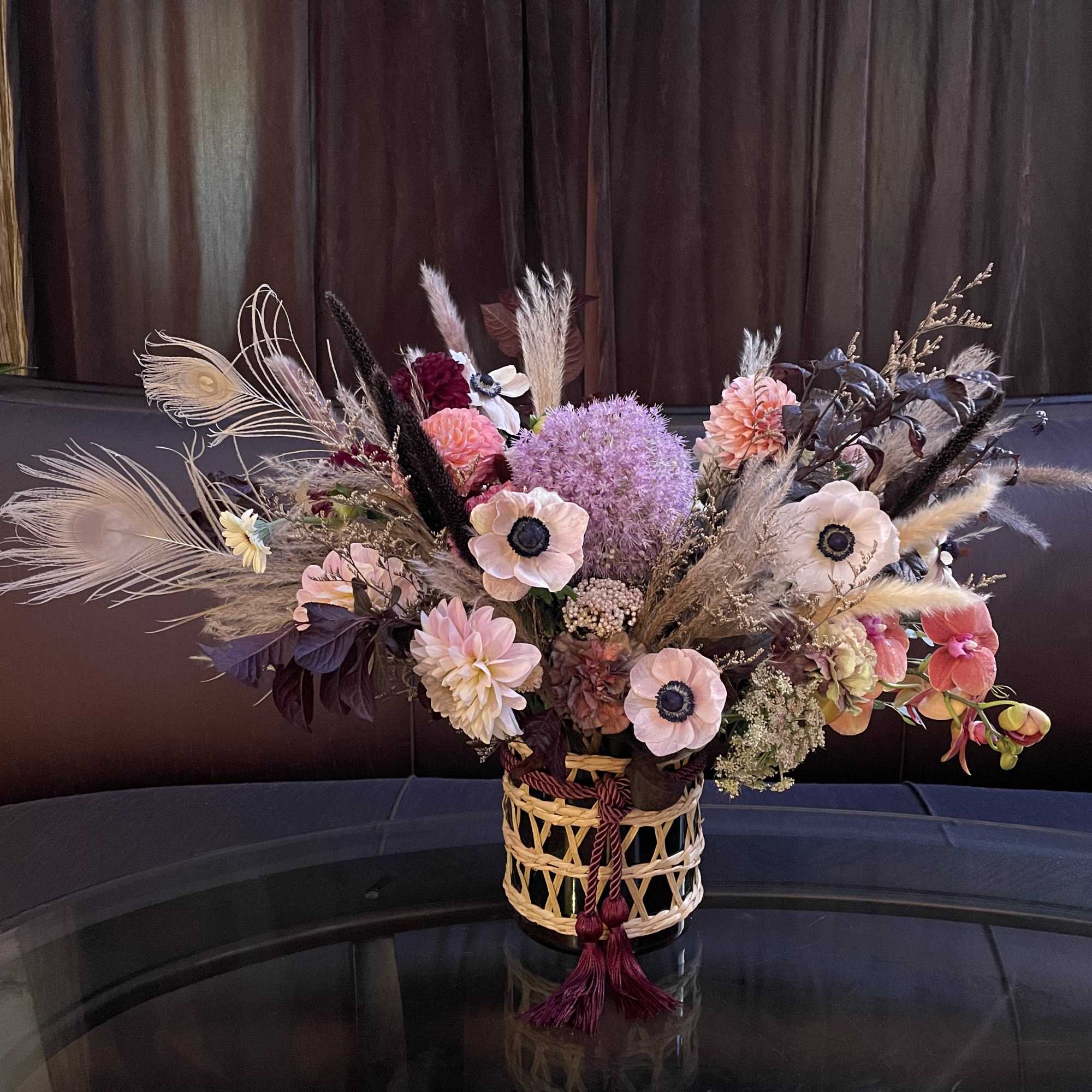 Large mixed floral arrangement in a woven basket with dried grasses and pastel blooms