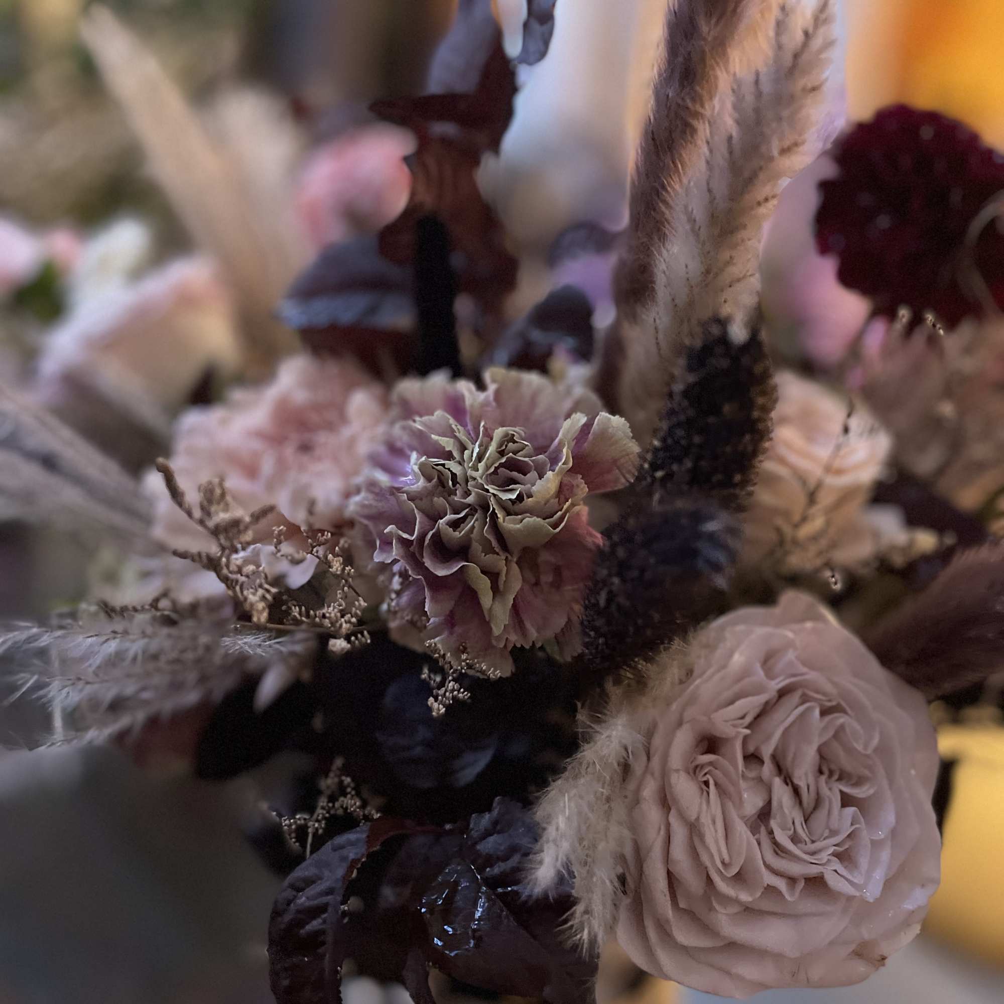 Muted pink and burgundy floral arrangement with dried grasses and roses