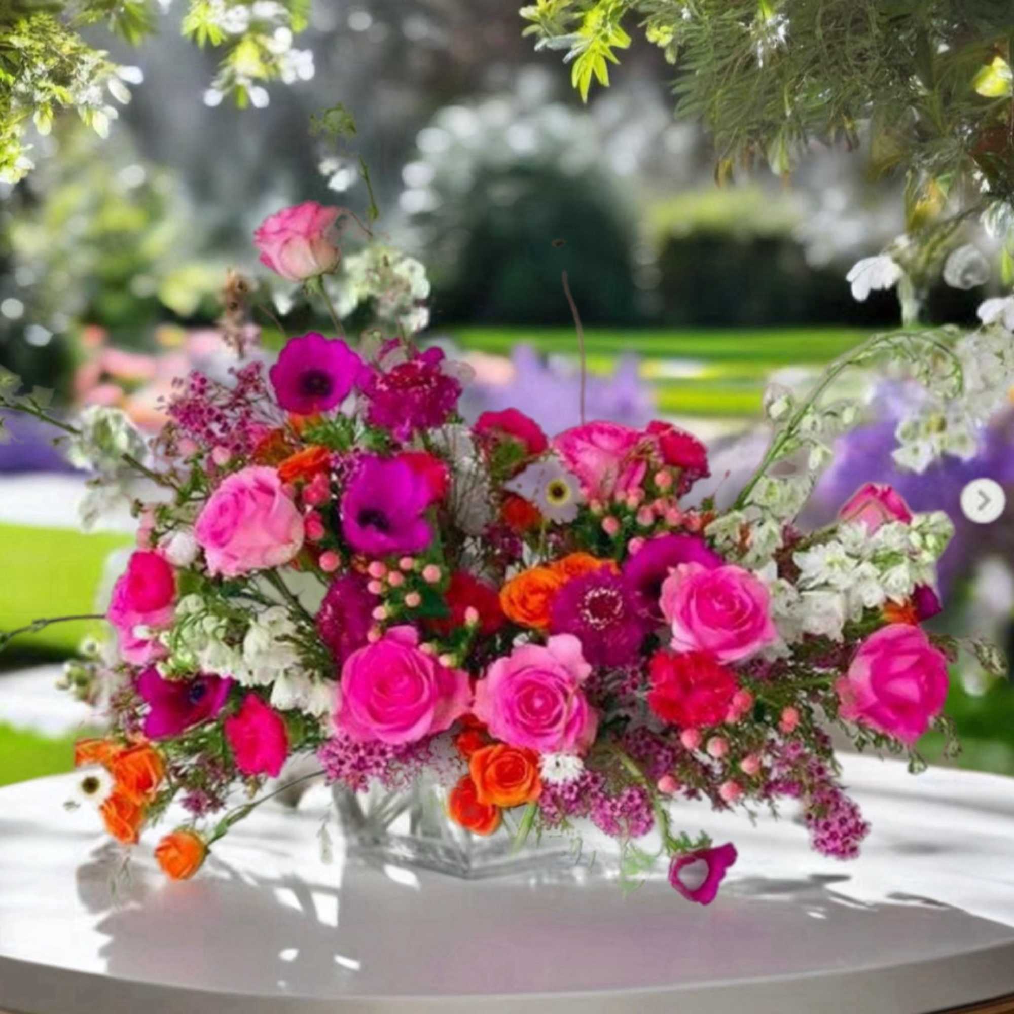 Bright pink and orange floral arrangement in a clear vase