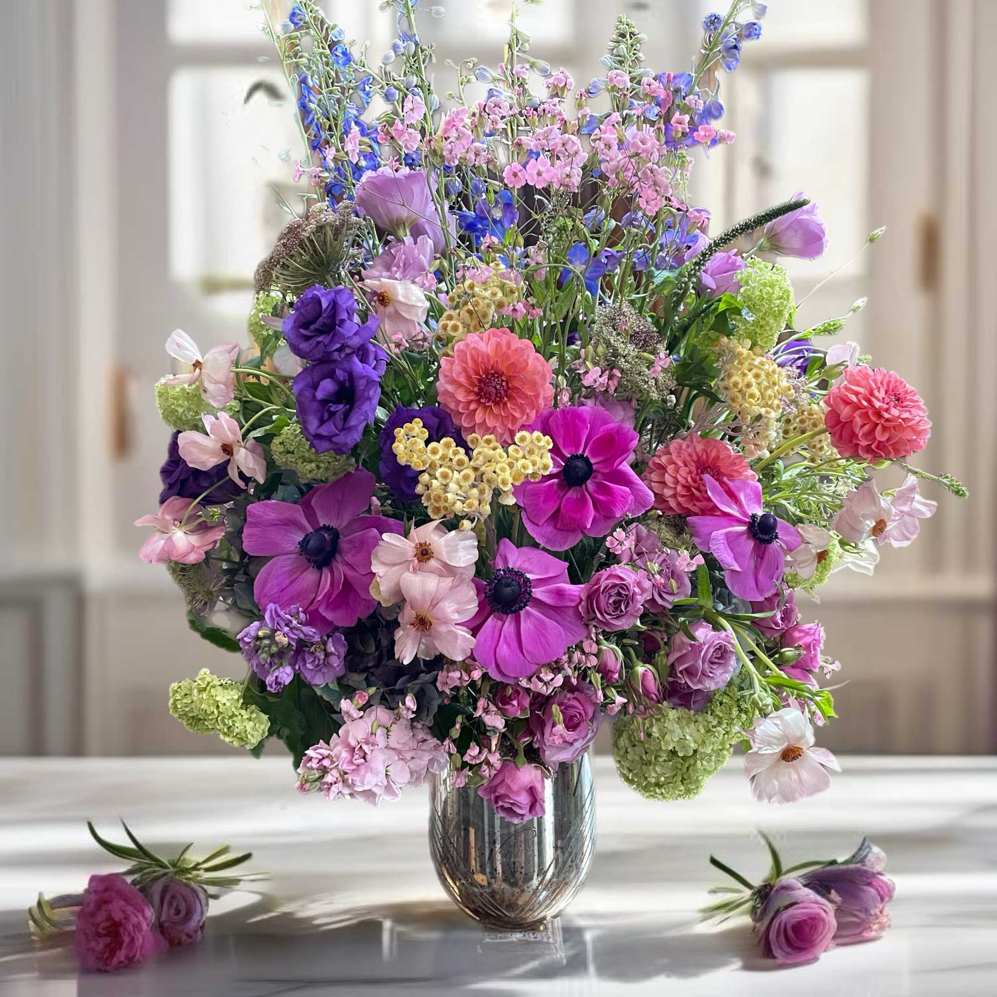 Large mixed bouquet of pink, purple, and blue flowers in a glass vase