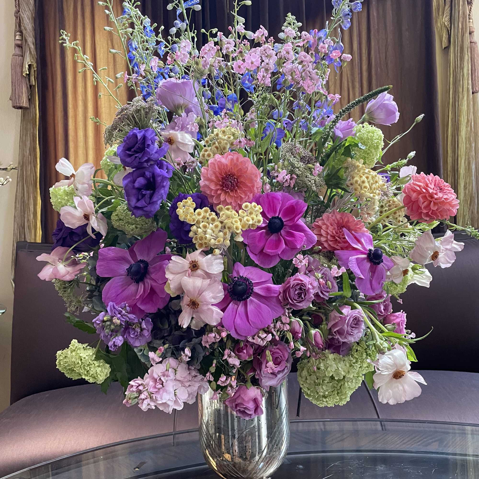 Large mixed bouquet in a silver vase with pink, purple, and blue flowers