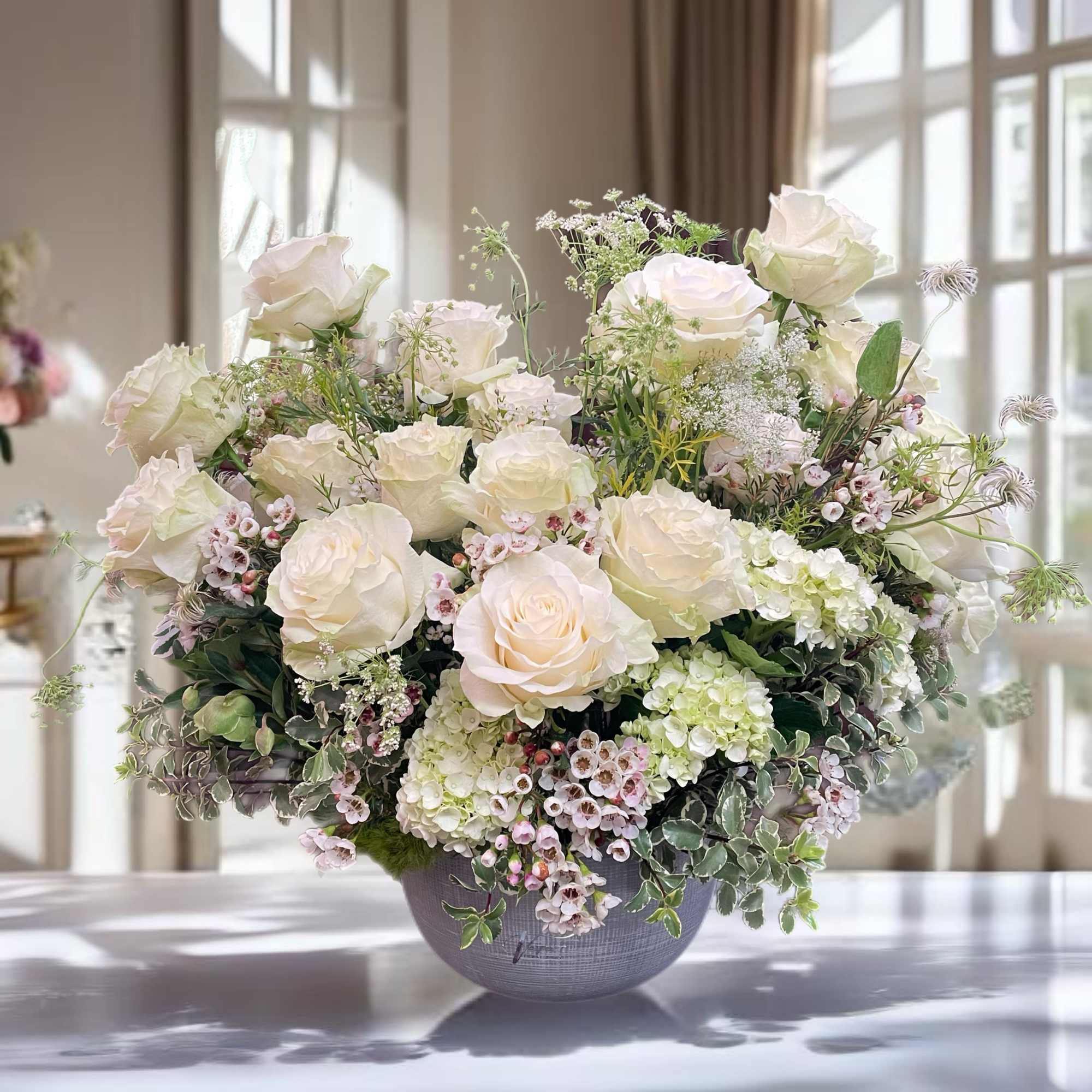 Cream rose arrangement in a gray vase with airy filler flowers