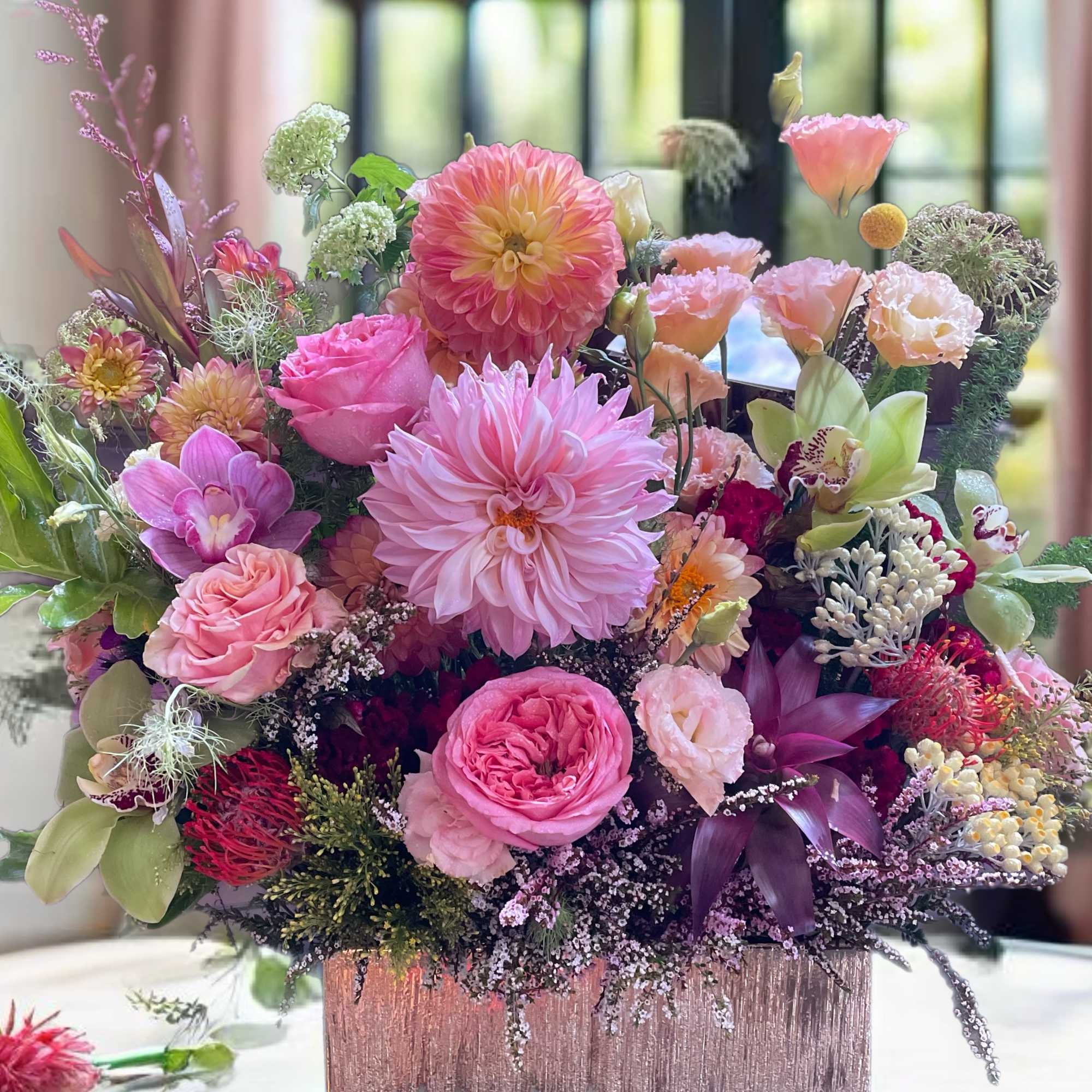 Pink and peach mixed flower arrangement in a square vase