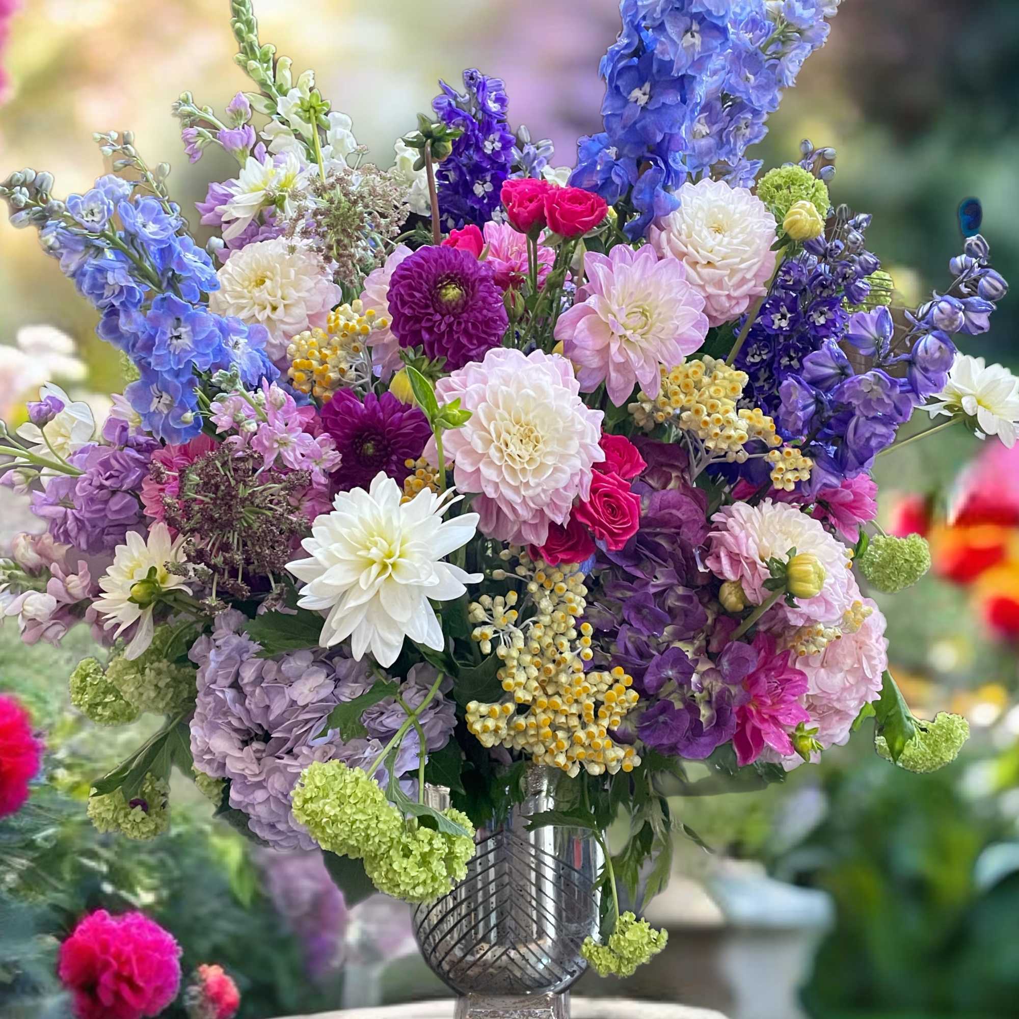 Colorful mixed bouquet in a clear vase with blue, purple, pink, and white blooms