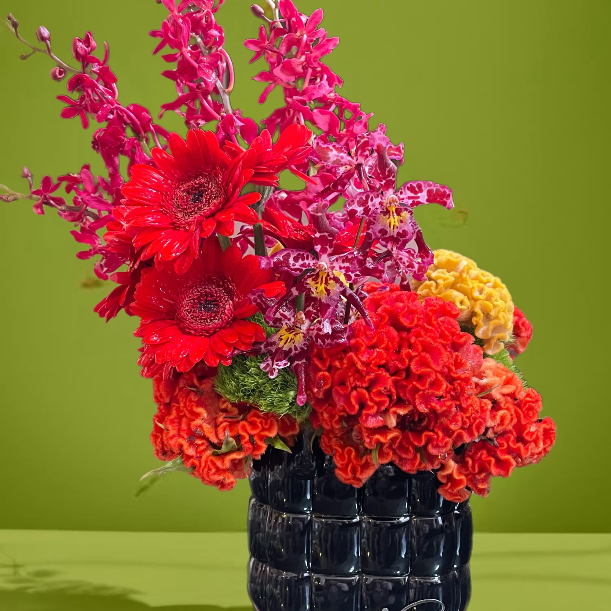 Bright mixed bouquet in a dark glass vase with red and pink blooms