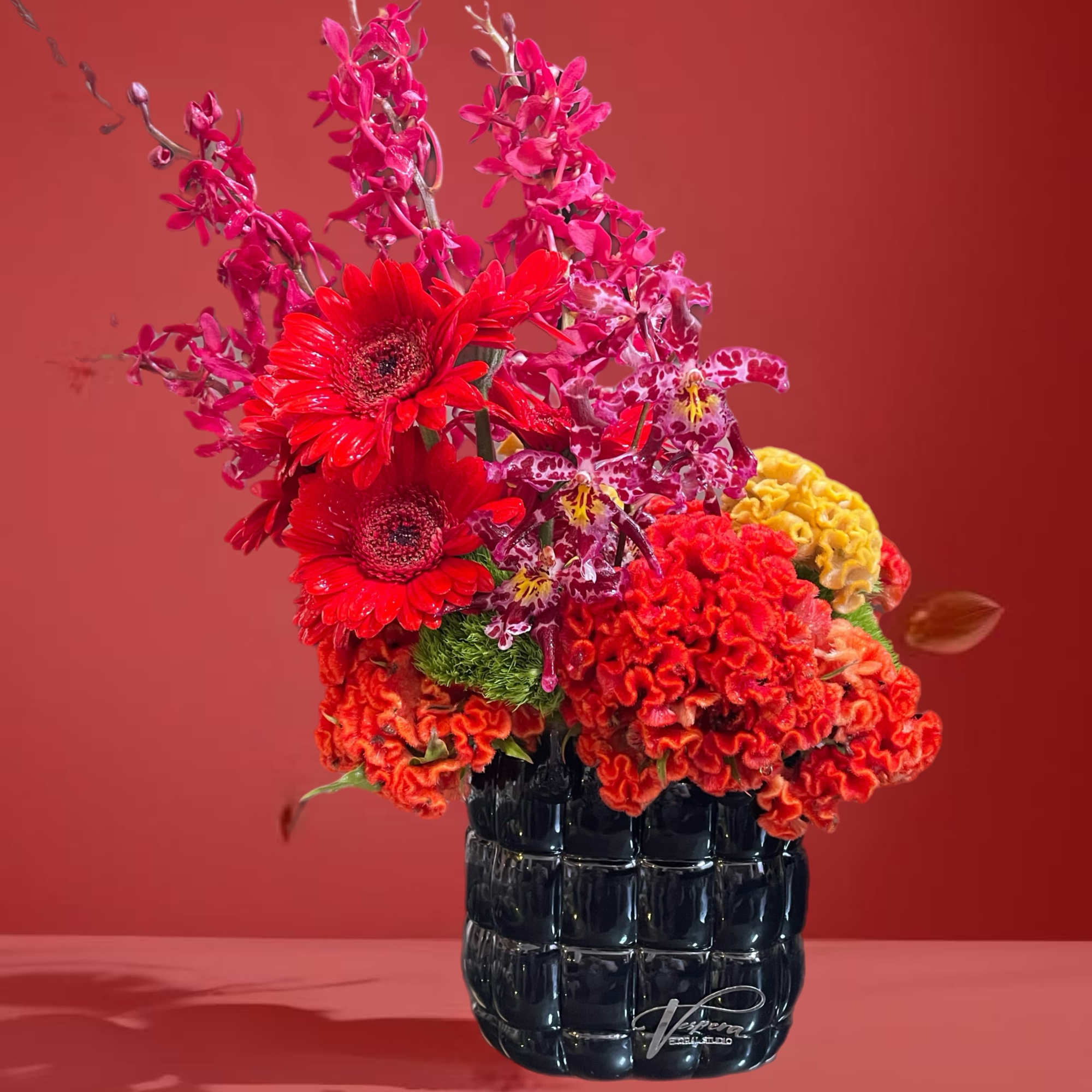Bright red and pink floral arrangement in a black vase, photo 3 of 4