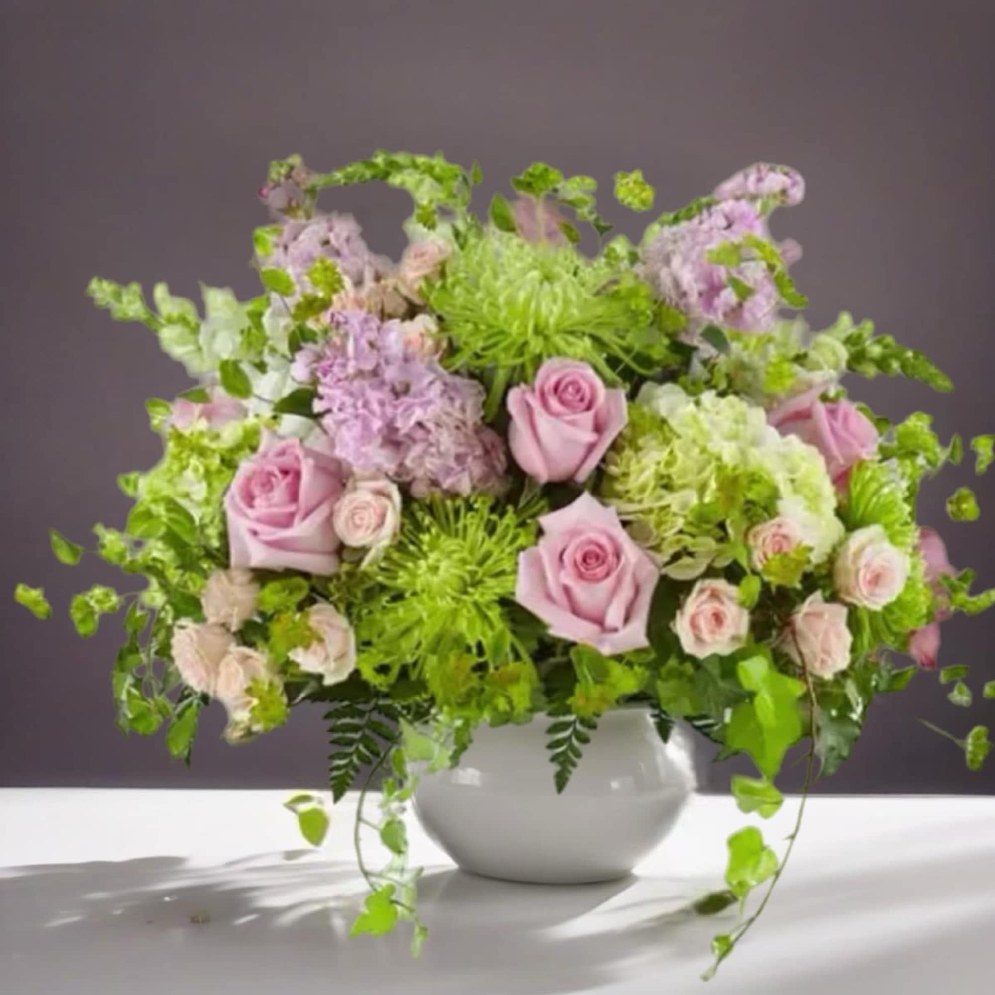 Pink roses and lavender flowers in a white vase
