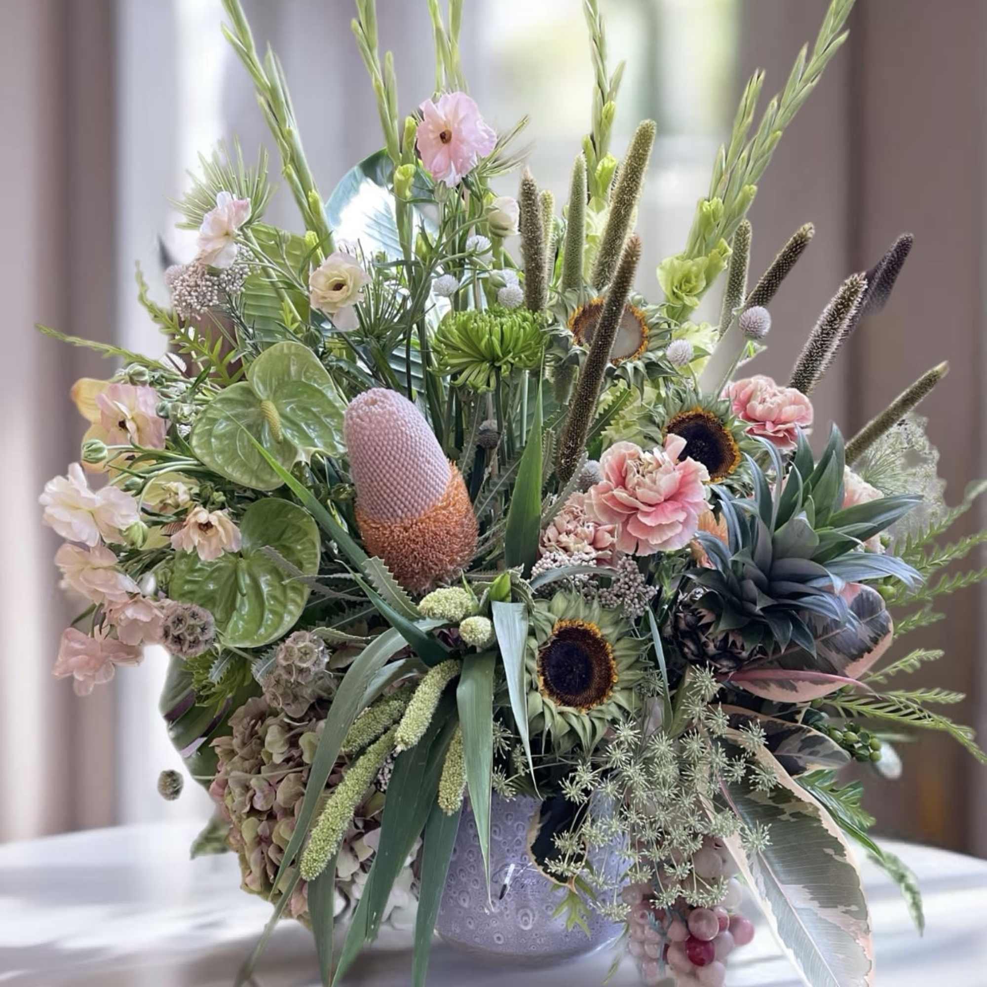 Large mixed floral arrangement in a decorative vase with pink and green blooms