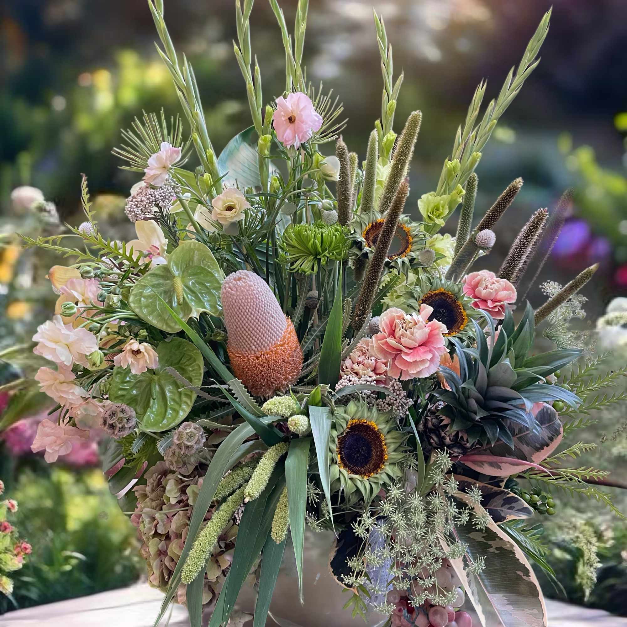 Large mixed floral arrangement in a white vase with pink and green blooms