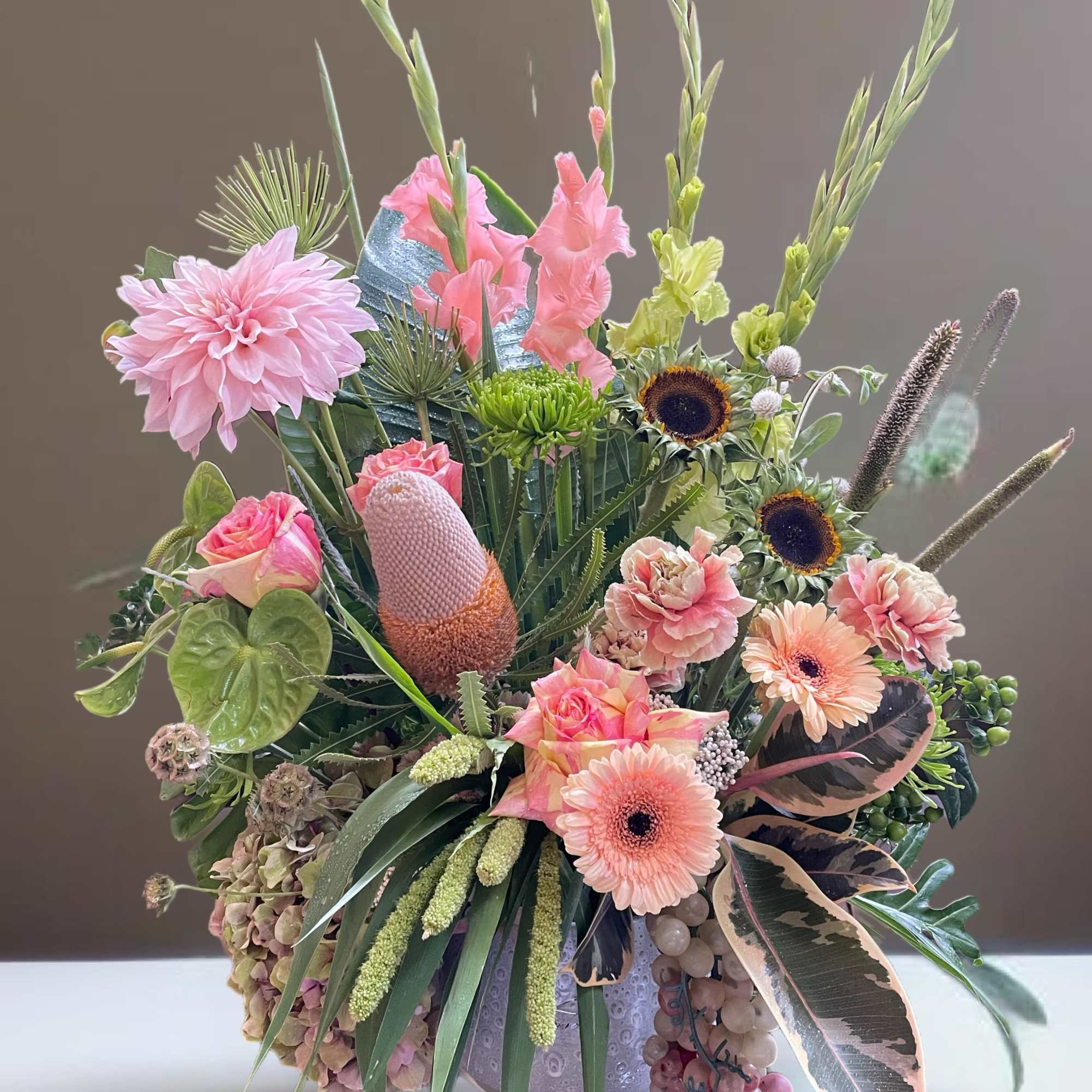 Mixed bouquet with pink blooms and tall green stems in a vase