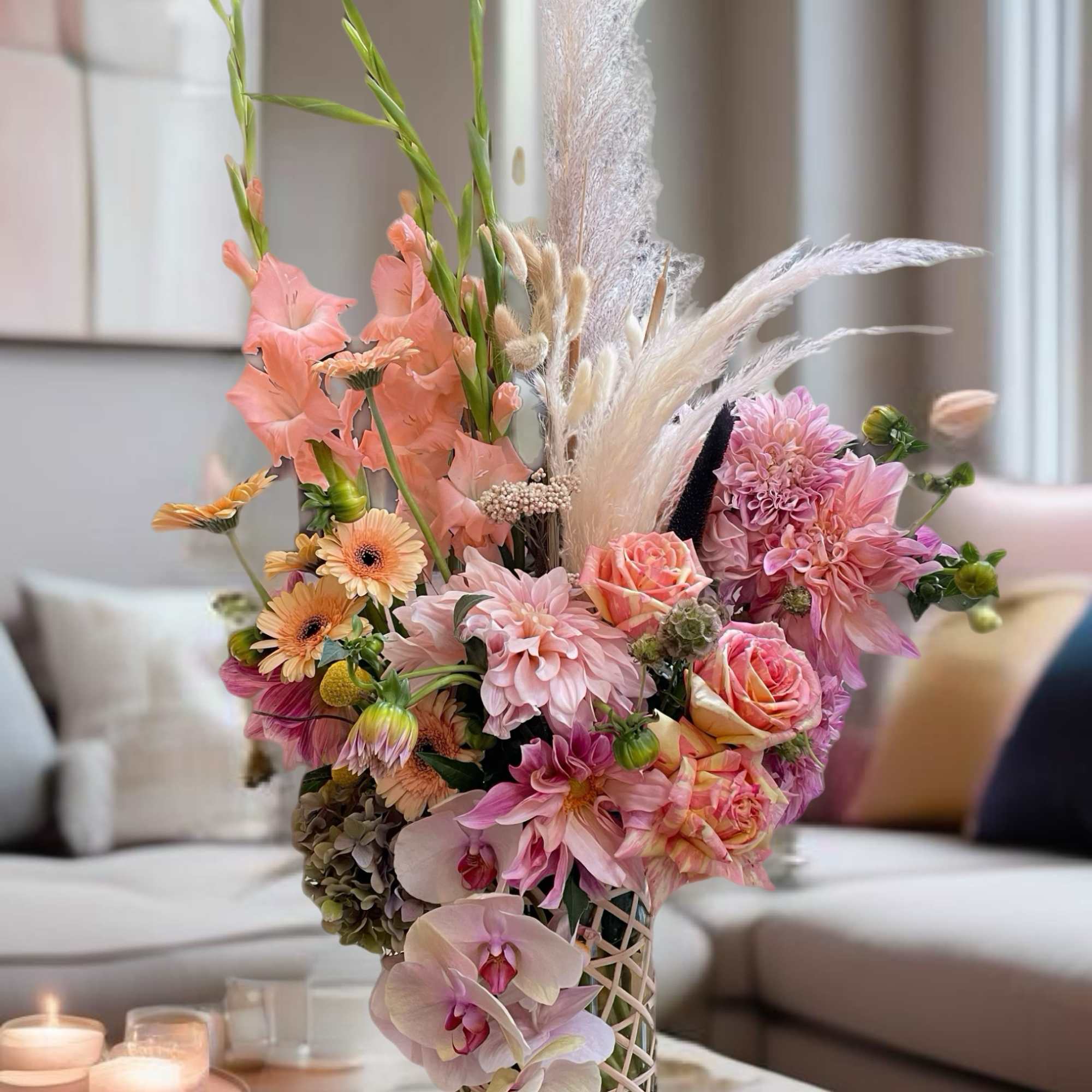 Pastel floral arrangement with orchids, roses, and dahlias in a lattice vase