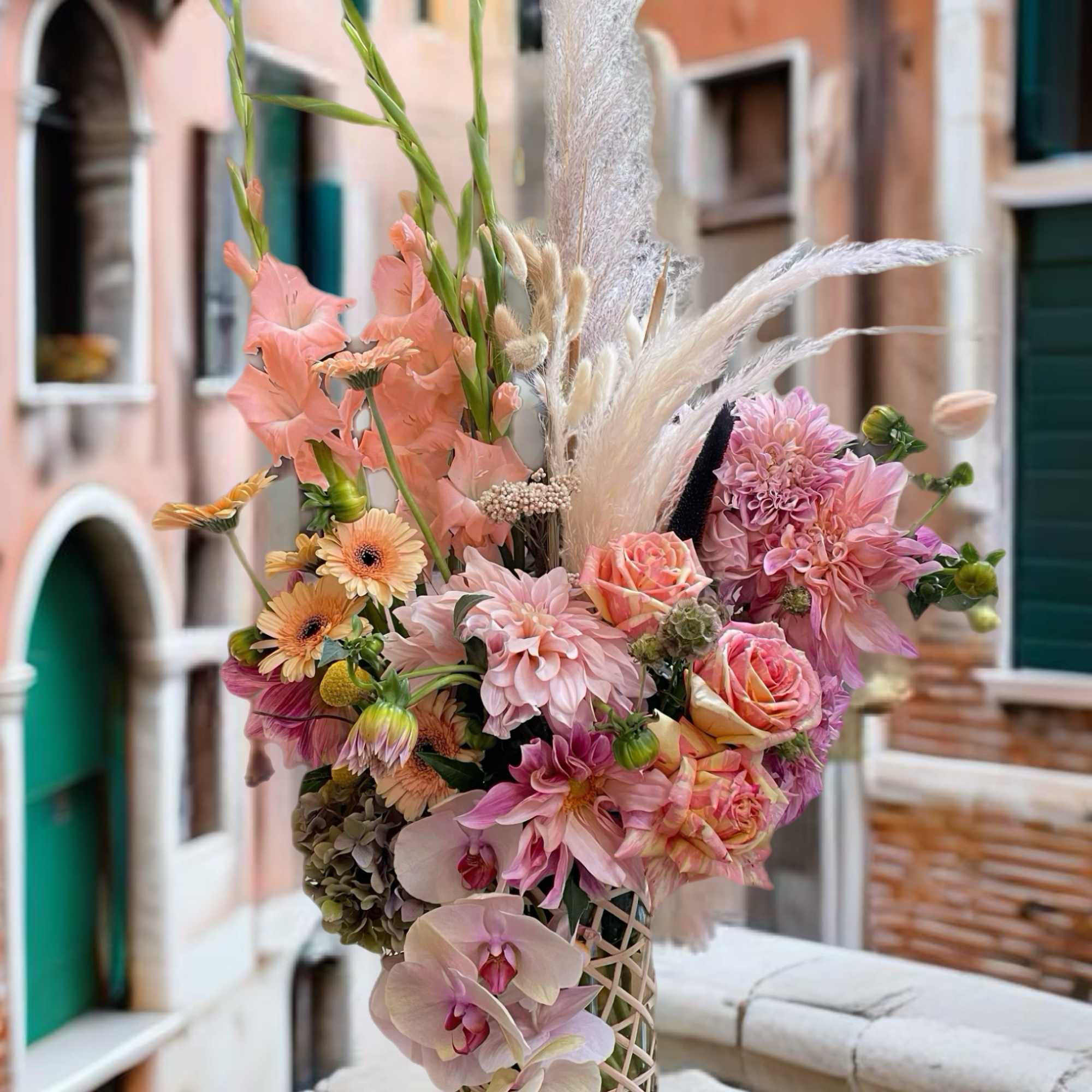 Pastel bouquet with orchids, roses, and pink blooms in a lattice vase