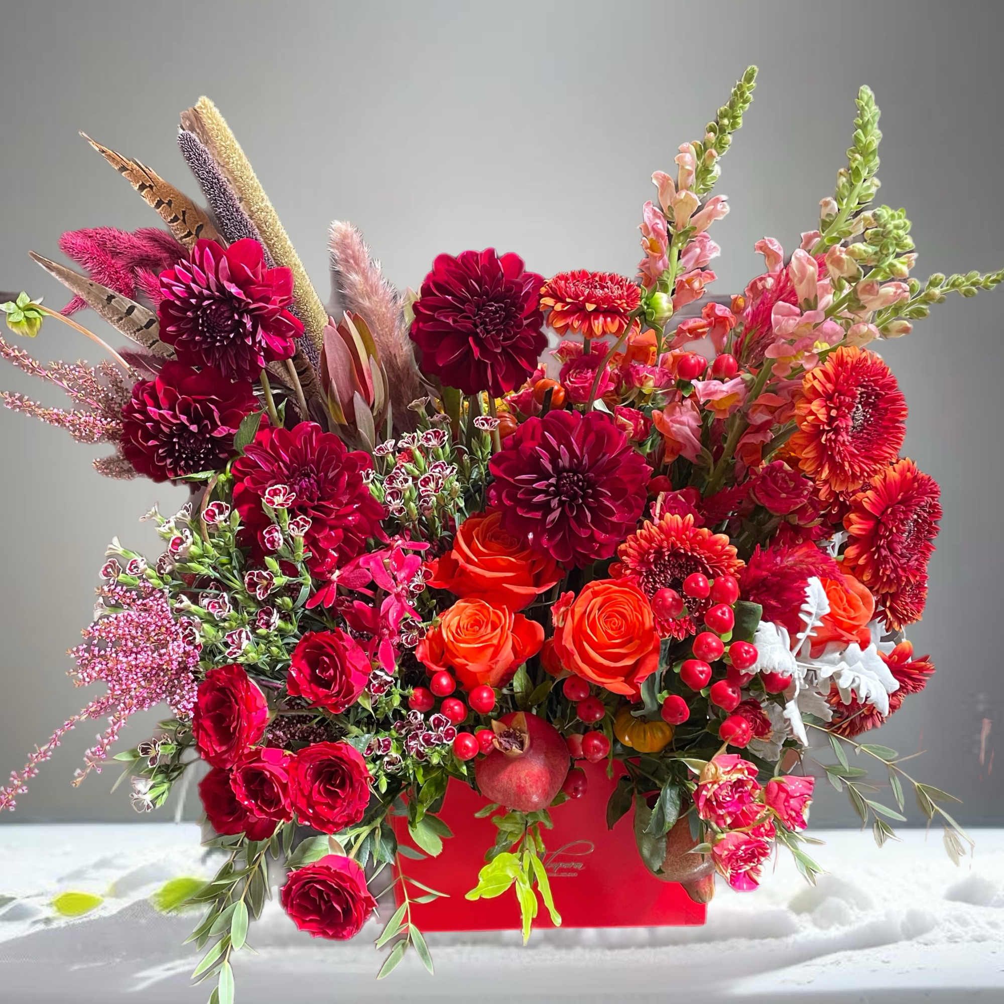 Vibrant red and orange floral arrangement in a red container