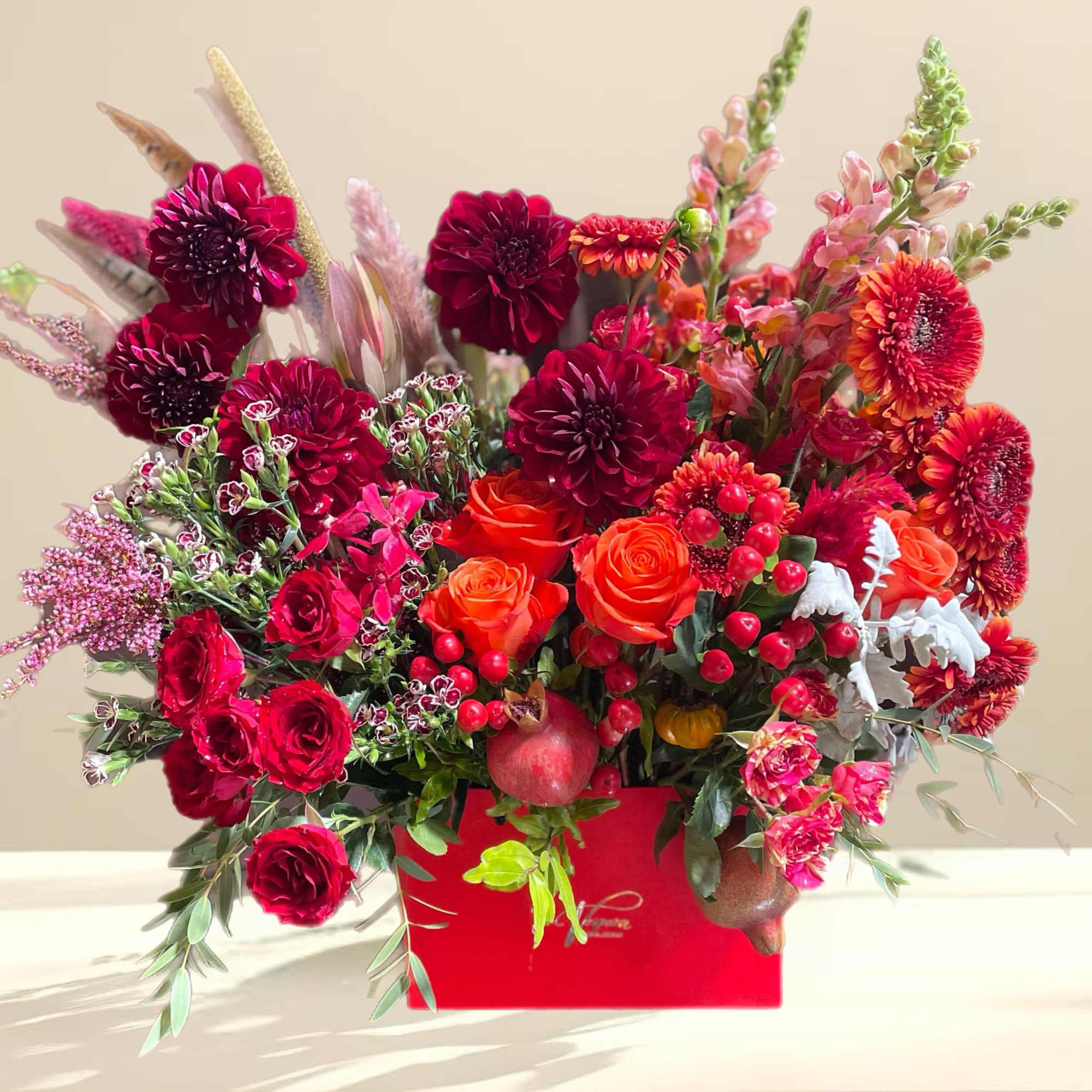 Bright mixed bouquet in a red box with roses and dahlias