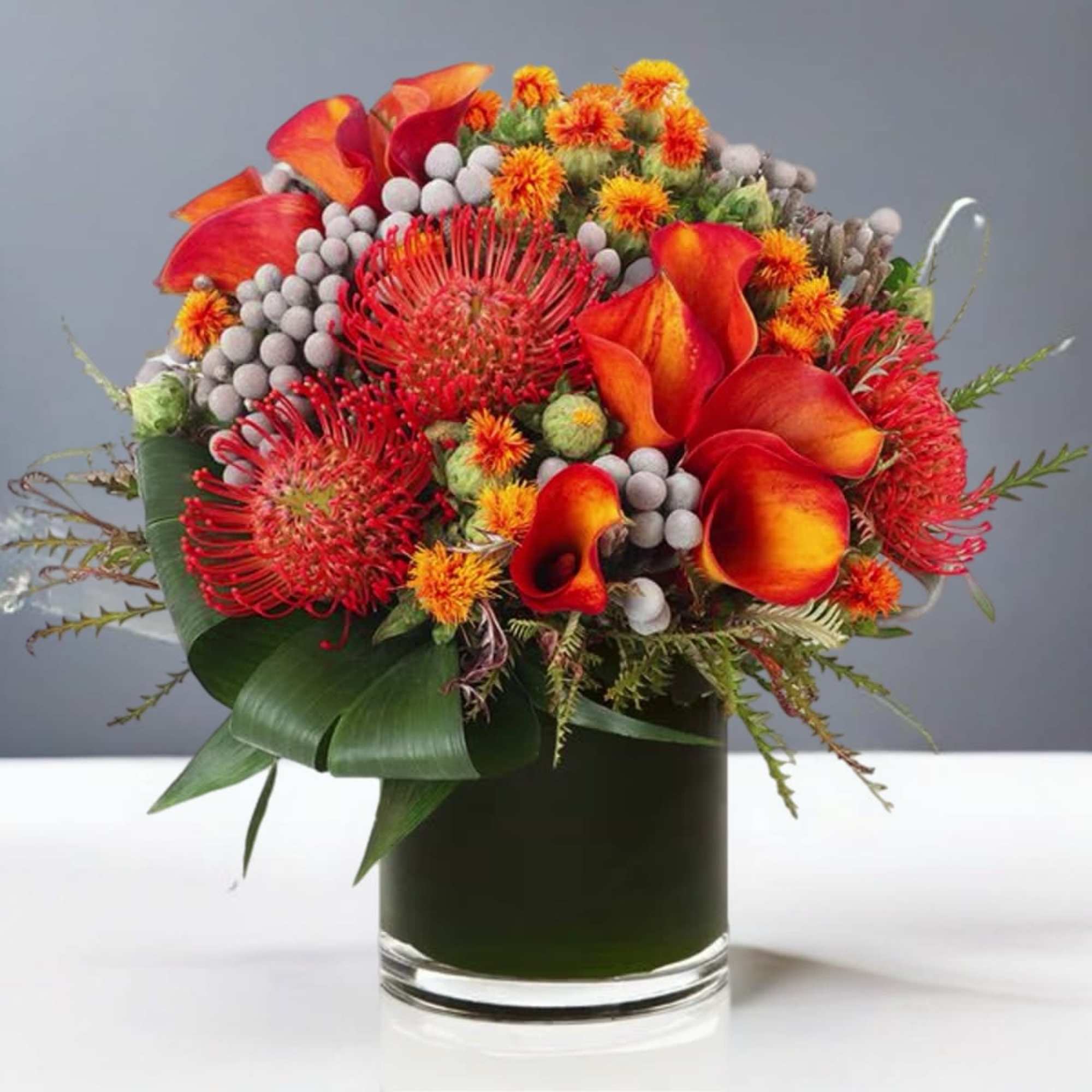 Orange and red tropical flowers arranged in a glass vase