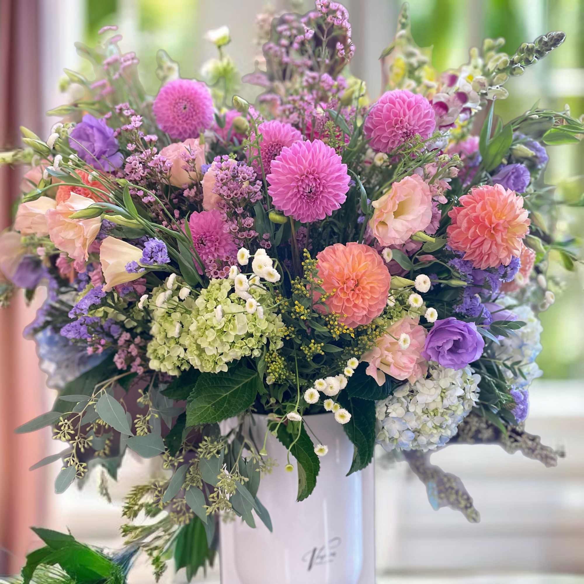 Mixed pastel bouquet in a white vase with pink, purple, and peach blooms