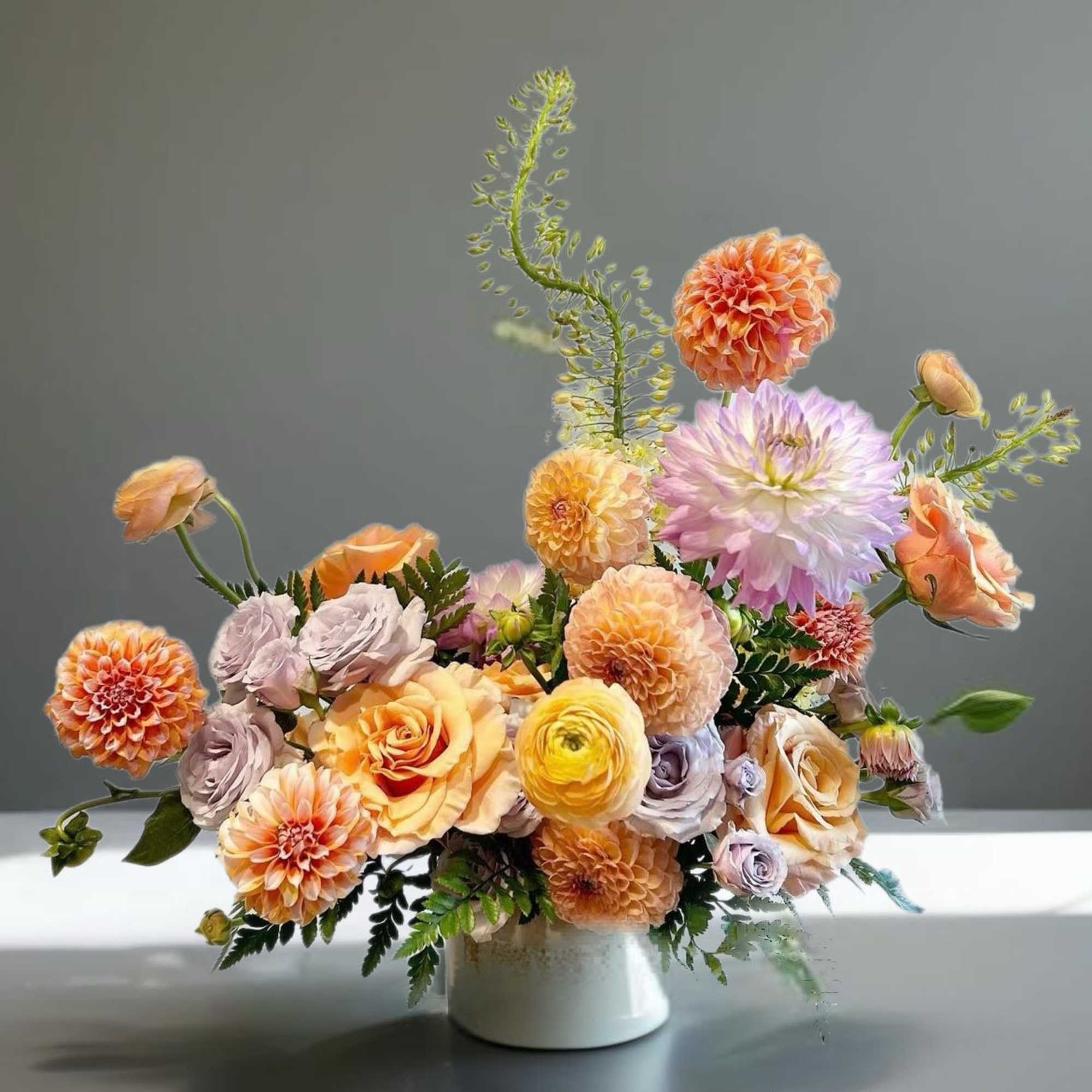 Peach and lavender flower arrangement in a white vase