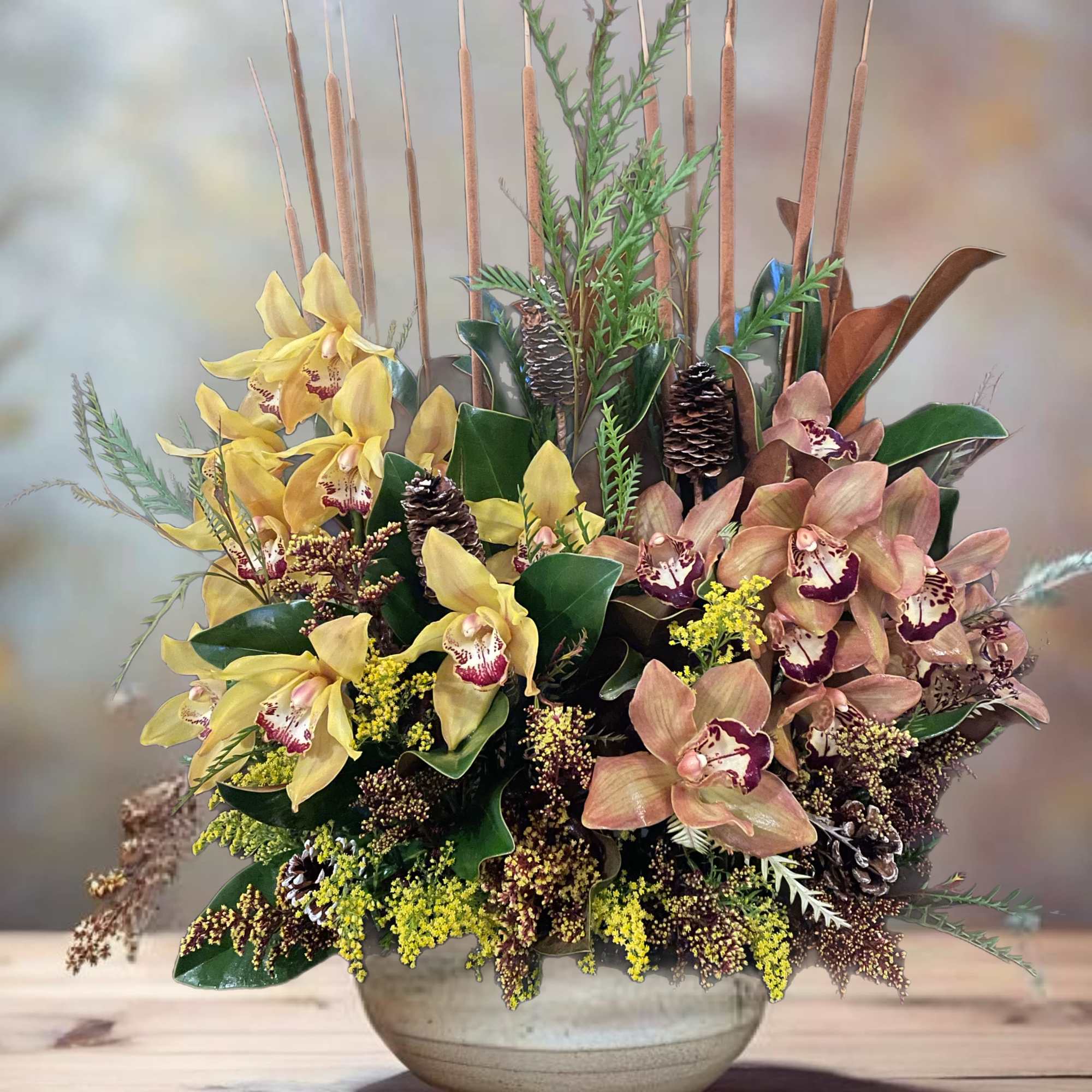 Arrangement of yellow and peach orchids in a ceramic bowl