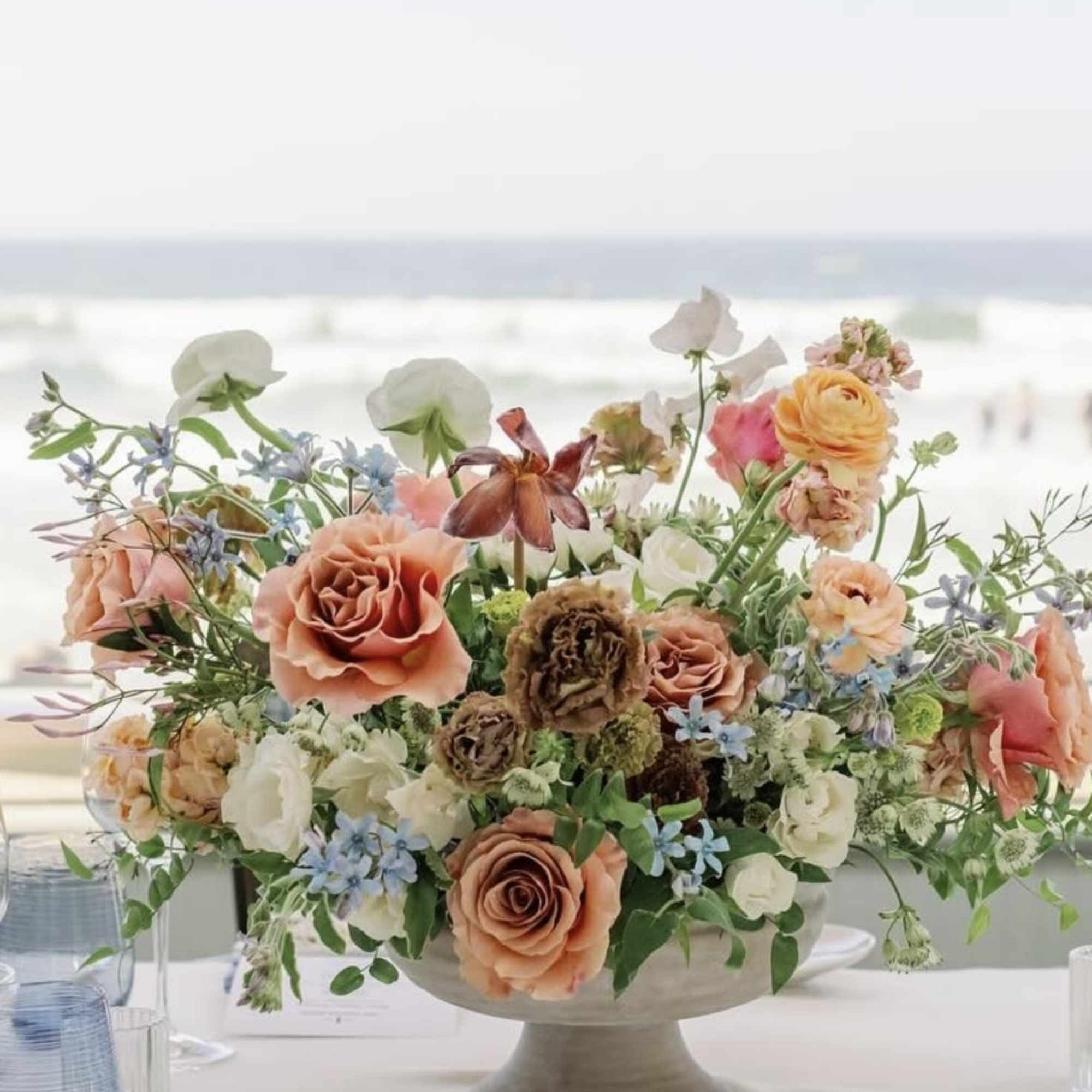 Peach and white floral centerpiece in a pedestal bowl