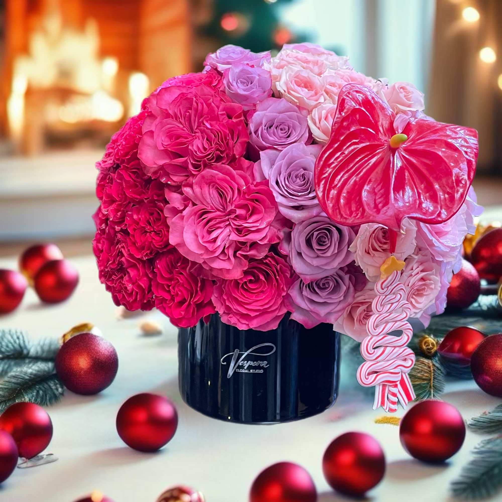 Pink and lavender rose arrangement in a dark vase with a red anthurium