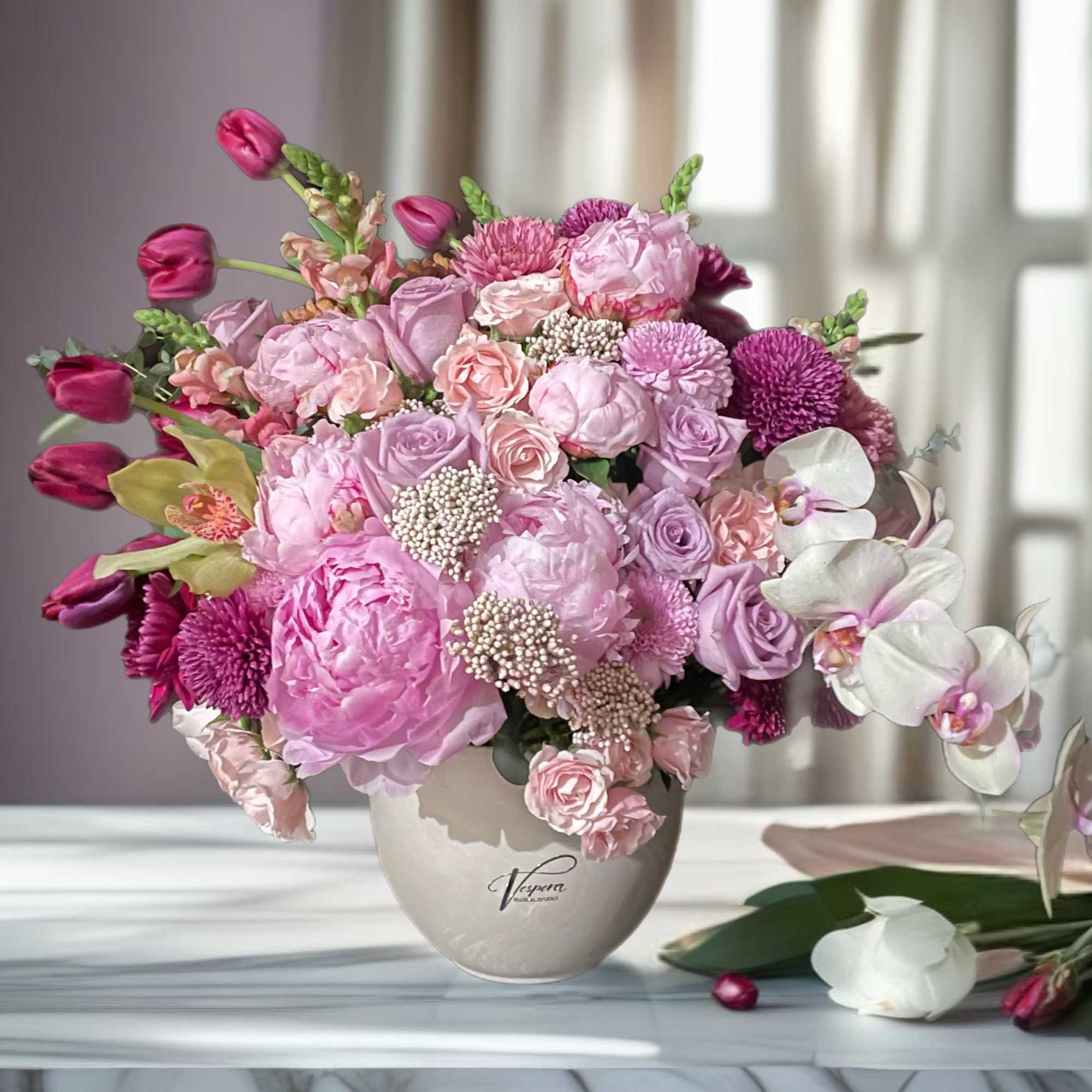 Pink and lavender flower arrangement in a beige vase