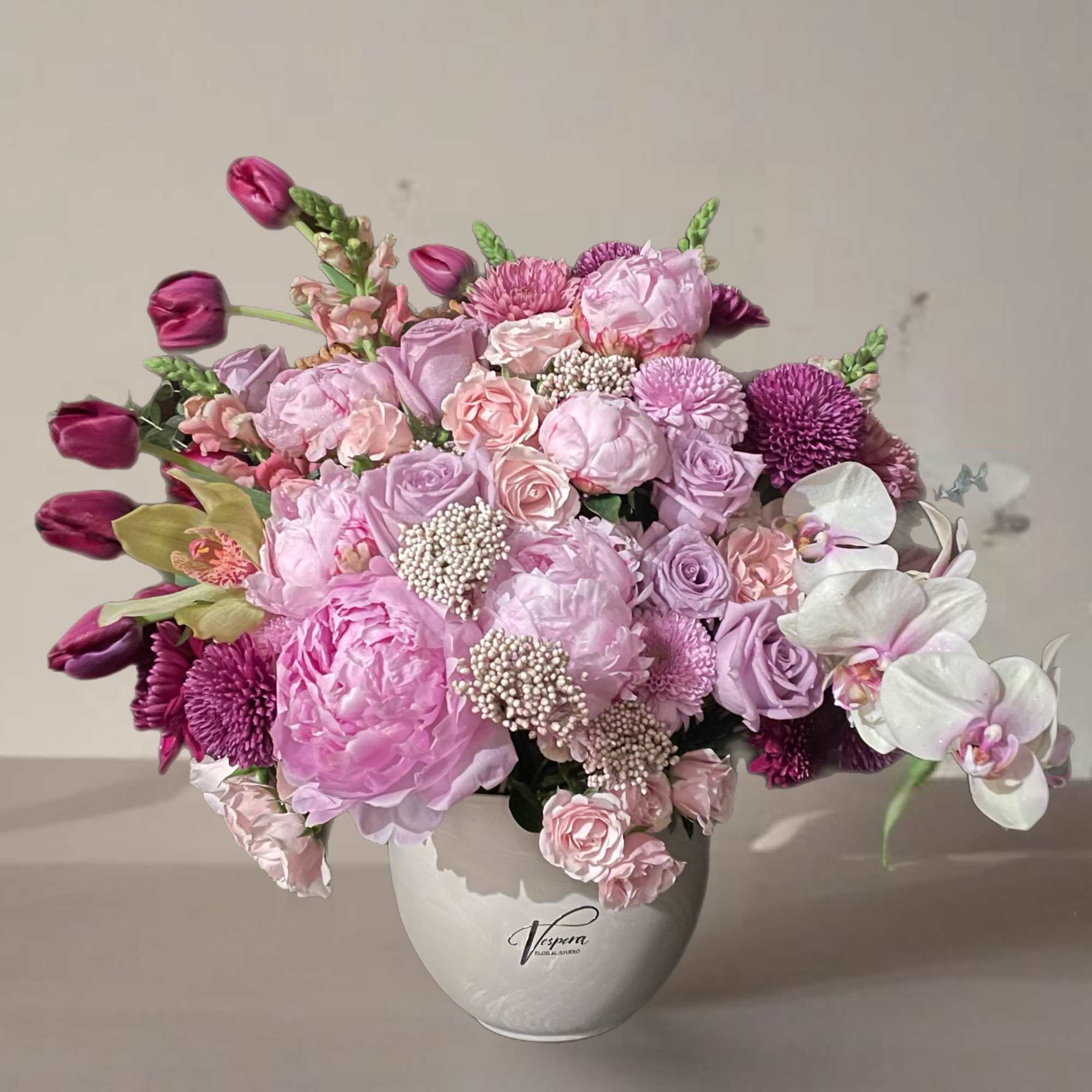 Pink and lavender bouquet in a white vase with white orchids
