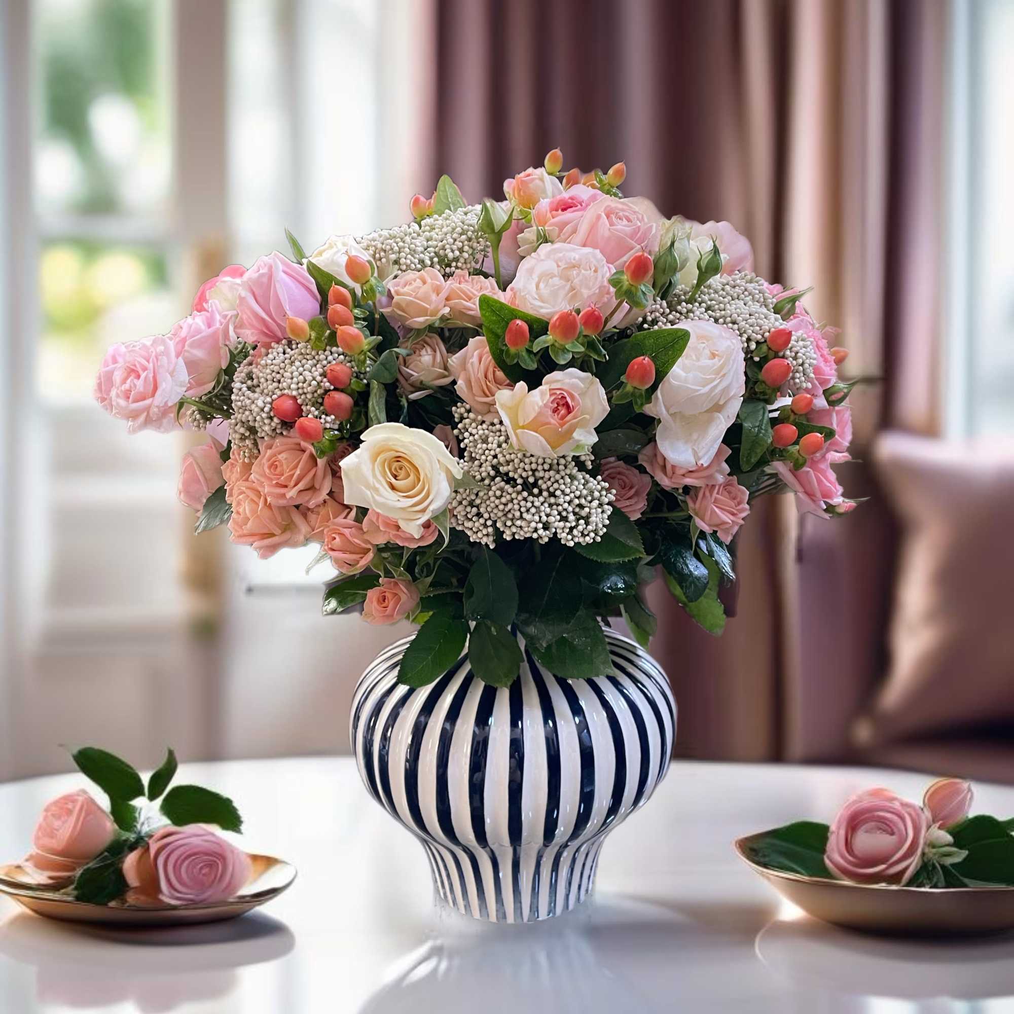 Pink and white rose arrangement in a striped ceramic vase