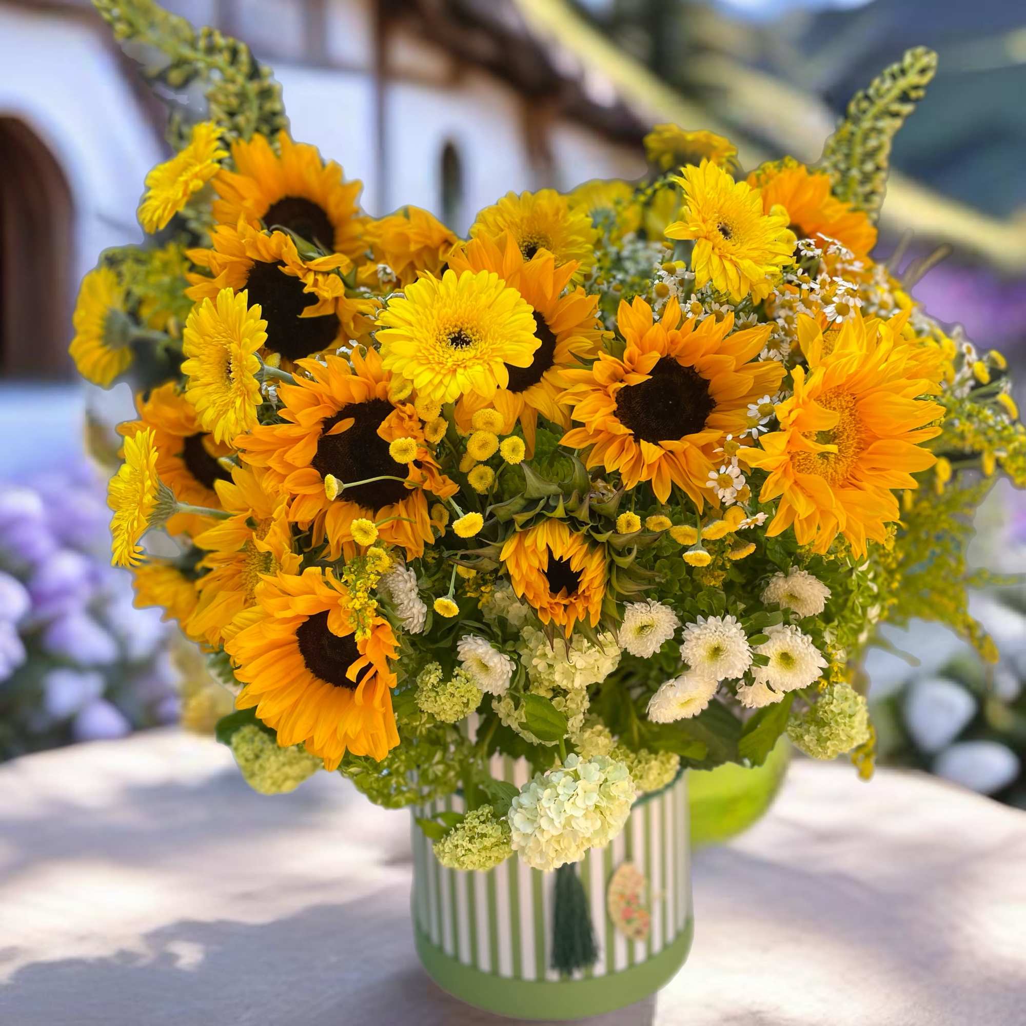 Bouquet of sunflowers and yellow daisies in a striped vase