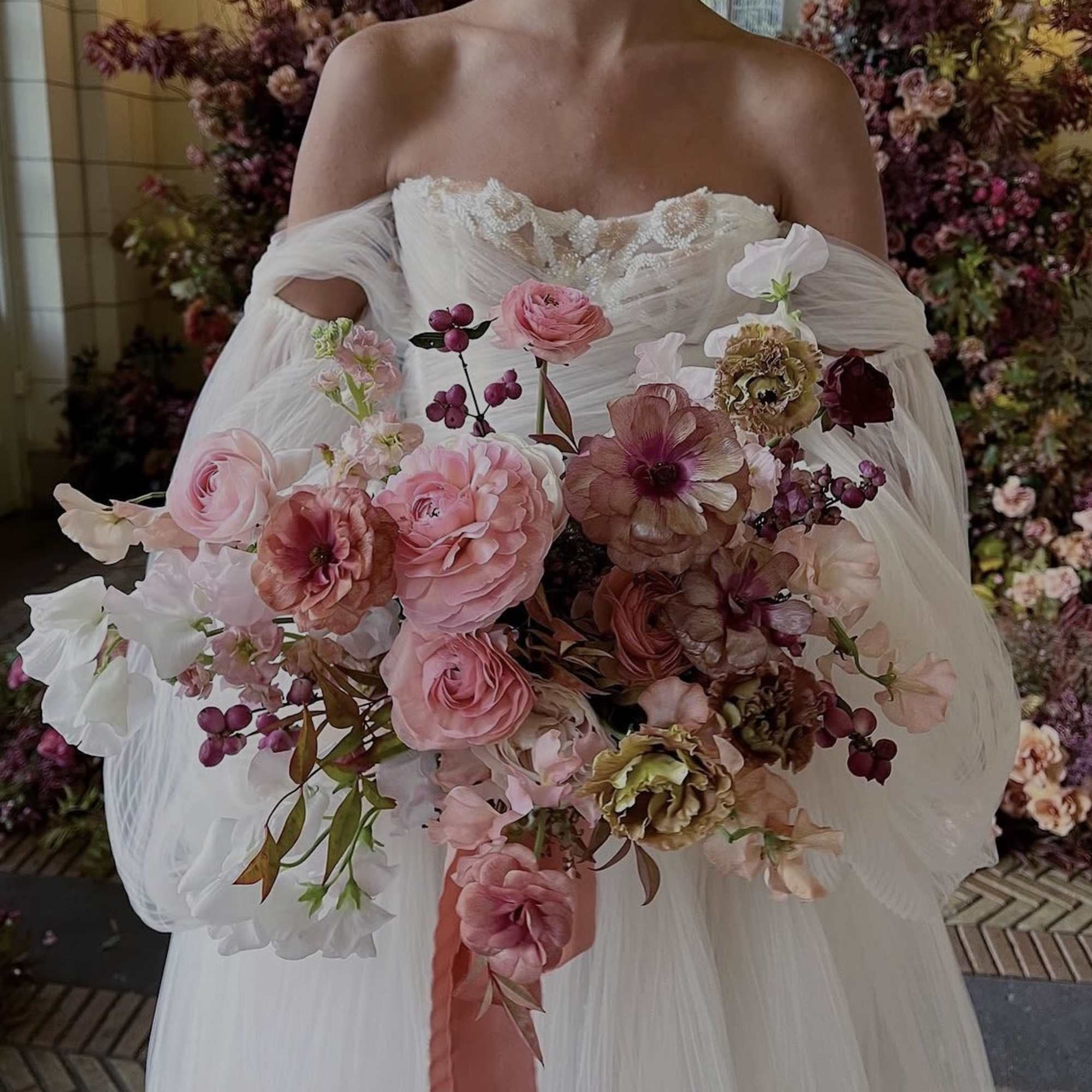 Bride holding a large pink and burgundy bouquet with a ribbon tail