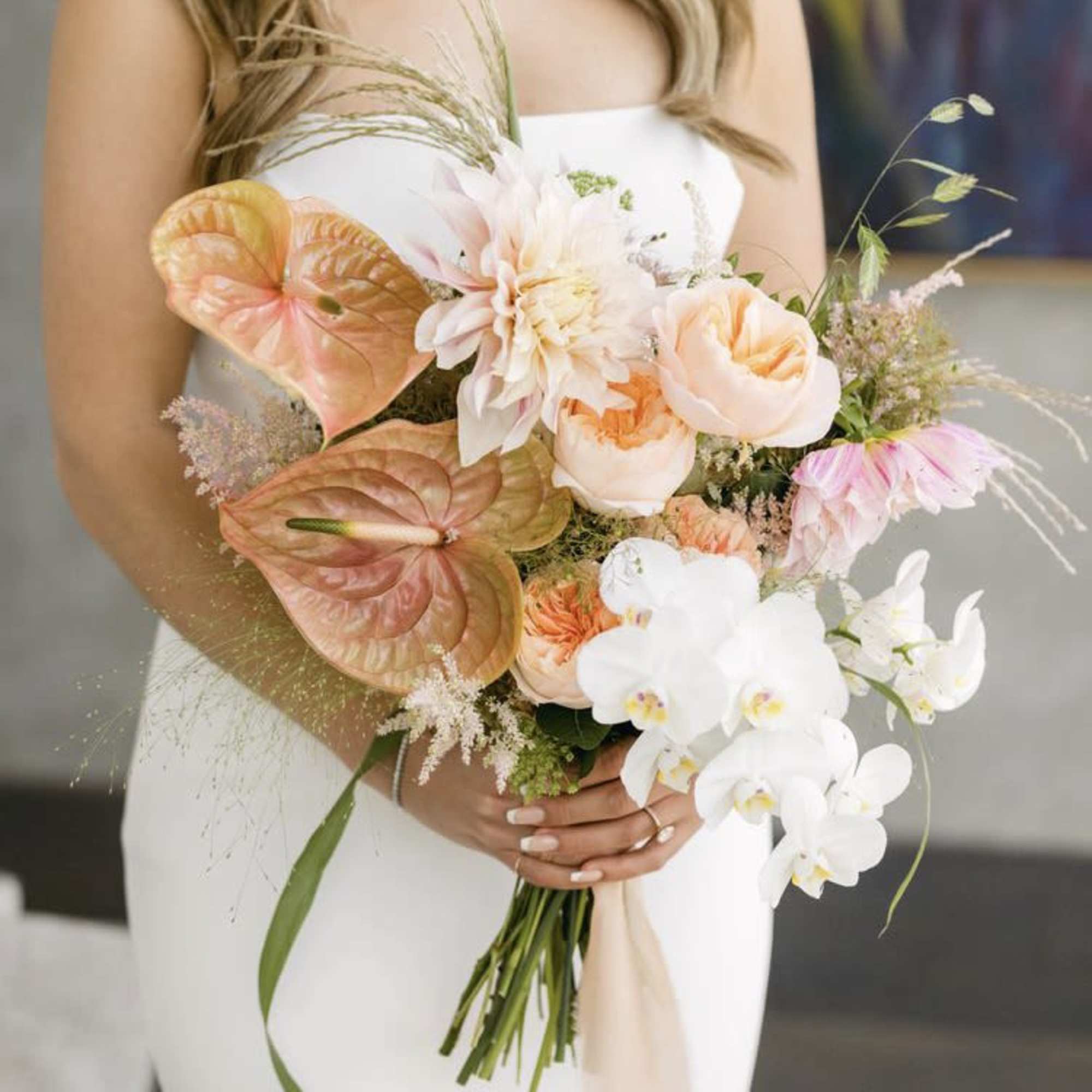 Bride holding a pastel bouquet with orchids and peach blooms