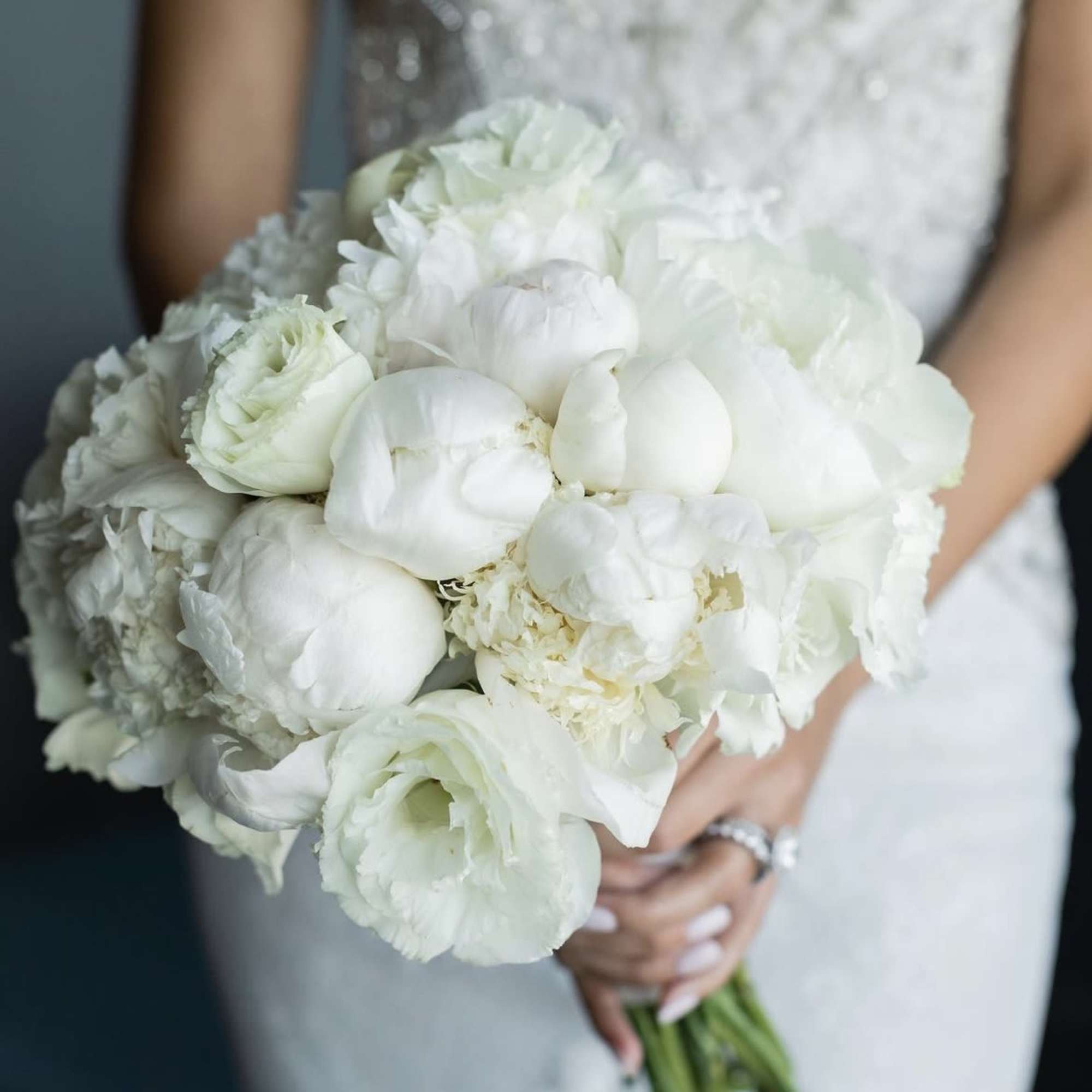 Bride holding a white bouquet of peonies and roses