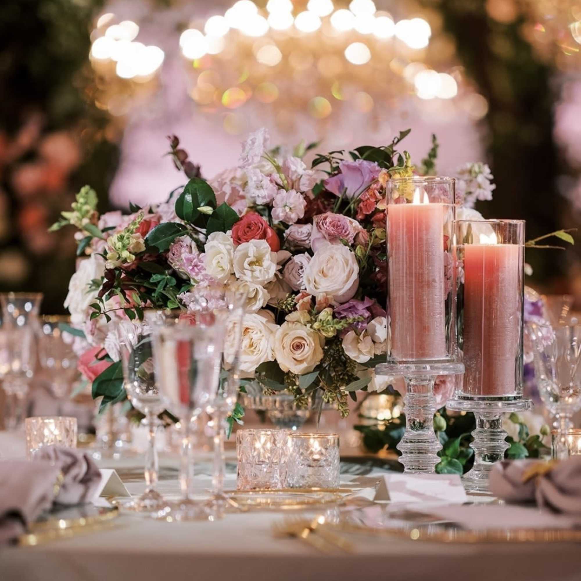 Pink and white floral centerpiece with candles on a table